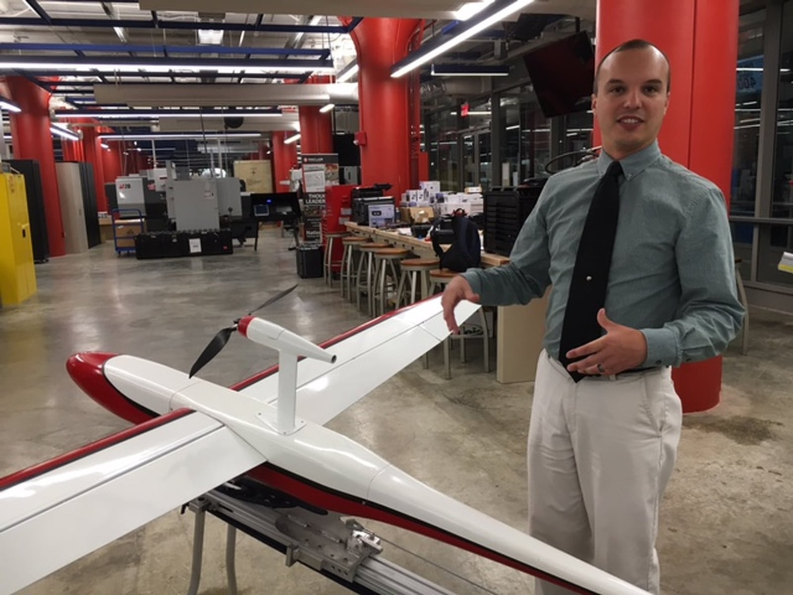 In this 2017 file photo, Andrew Shepherd, who heads Sinclair Community College’s unmanned aerial vehicles program, stands next to a version of Unmanned Solutions Technology’s Pelican II fixed-wing UAV. THOMAS GNAU/STAFF