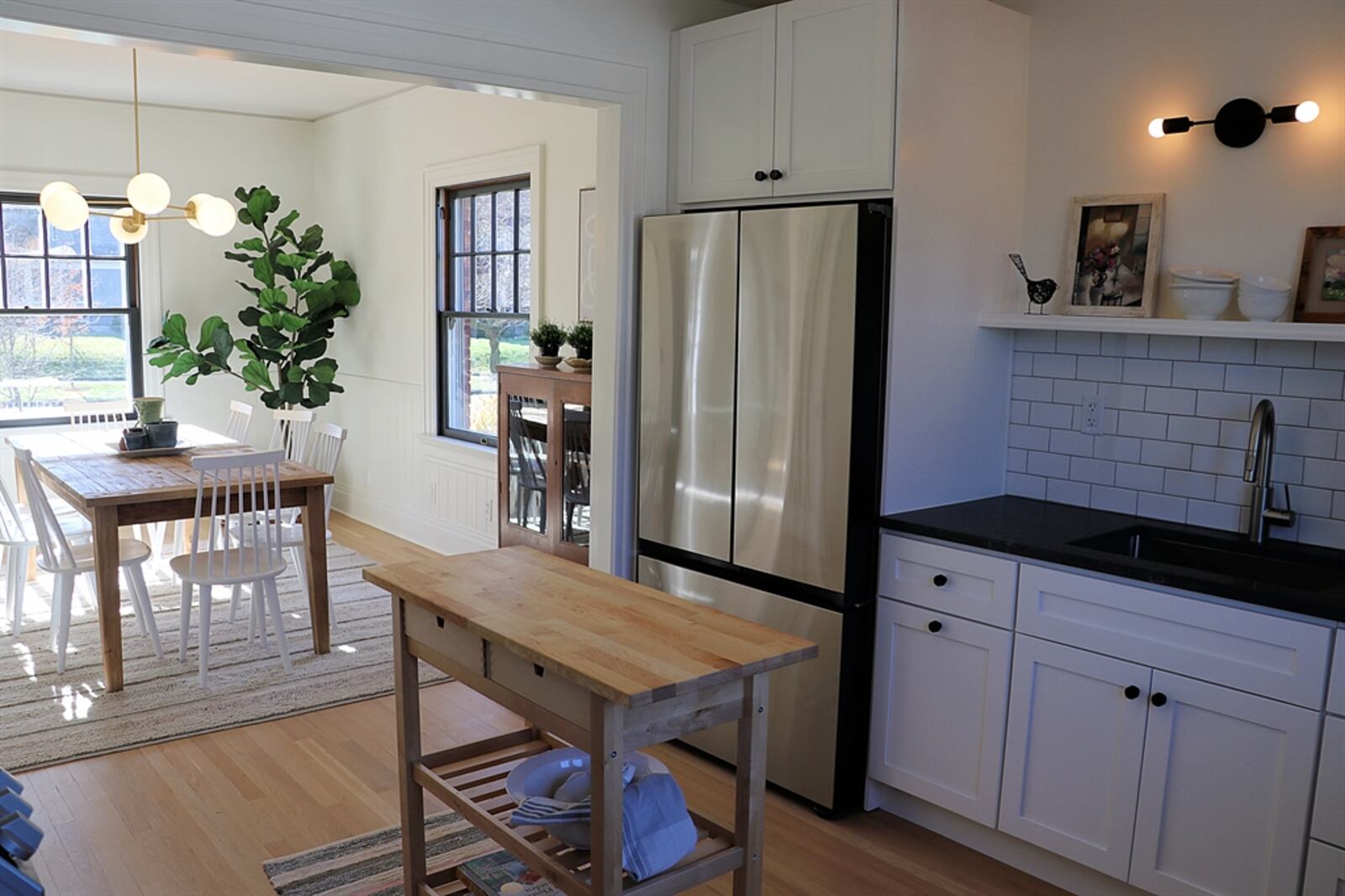 The kitchen has white cabinetry with black granite counters and subway-tile backsplash. Cabinetry and counters fill two walls and surround stainless-steel appliances.