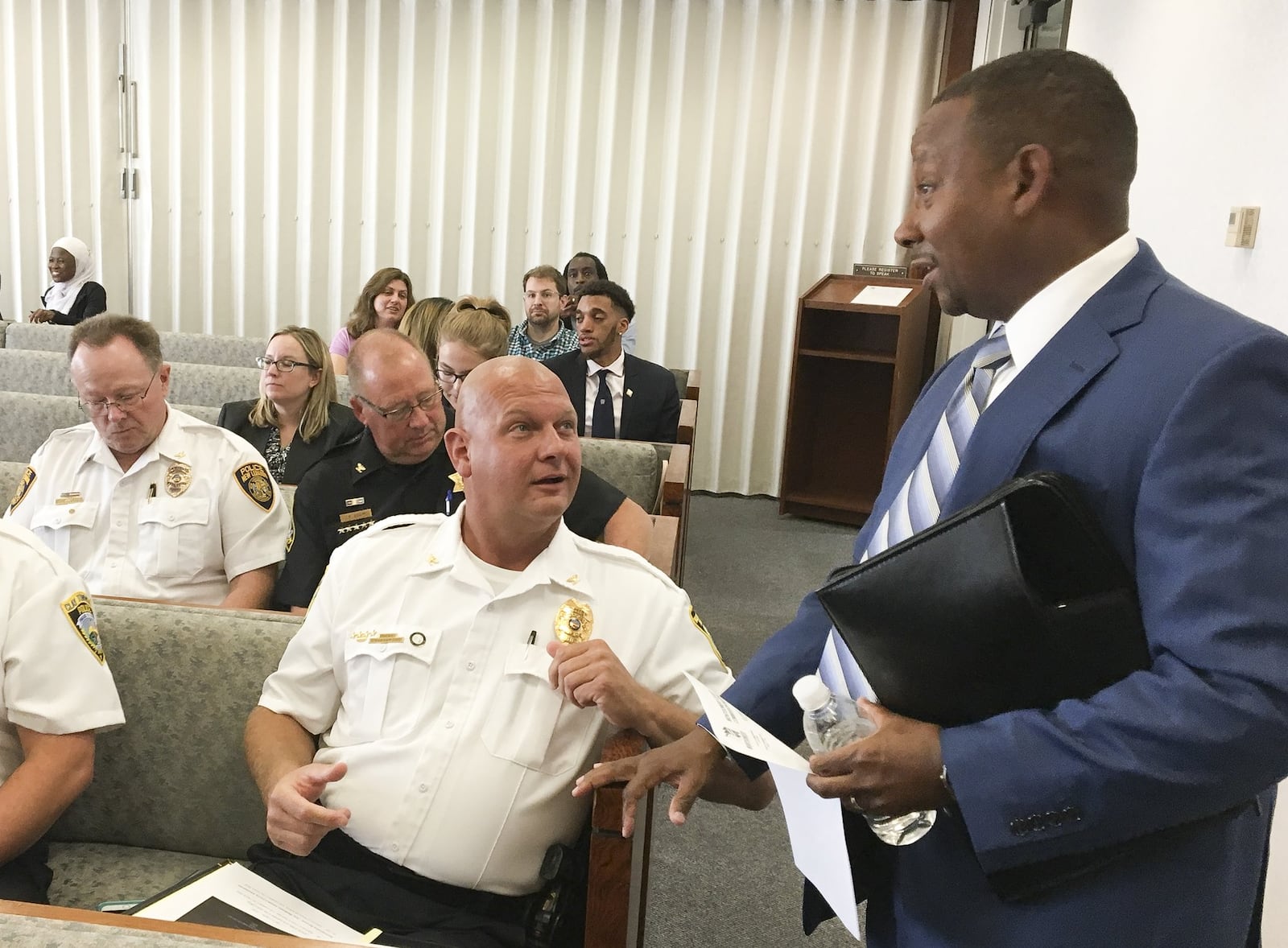 Brookville police Chief Douglas Jerome talks with Michael Colbert, who today is the Montgomery County administrator (standing in the photo), during a Montgomery County Commission meeting. CHRIS STEWART / STAFF