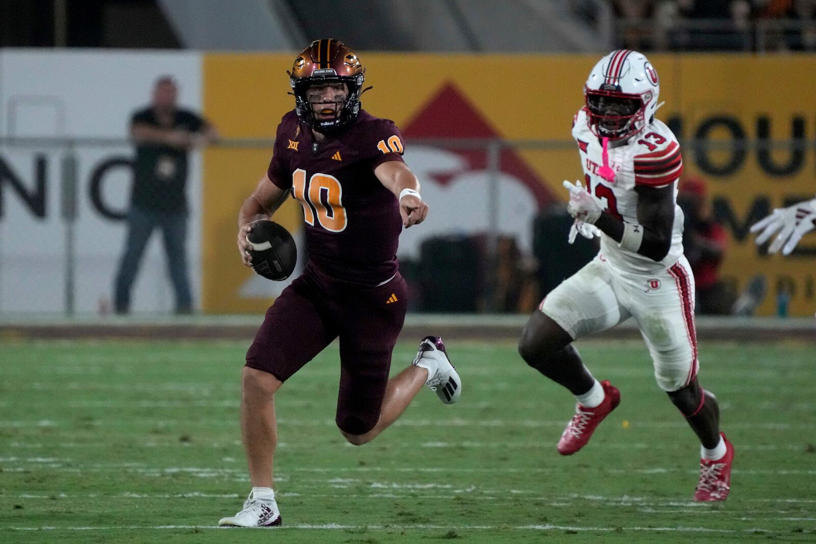 Arizona State quarterback Sam Leavitt (10) runs away from Utah safety Rabbit Evans in the first half during an NCAA college football game, Friday, Oct. 11, 2024, in Tempe, Ariz. (AP Photo/Rick Scuteri)