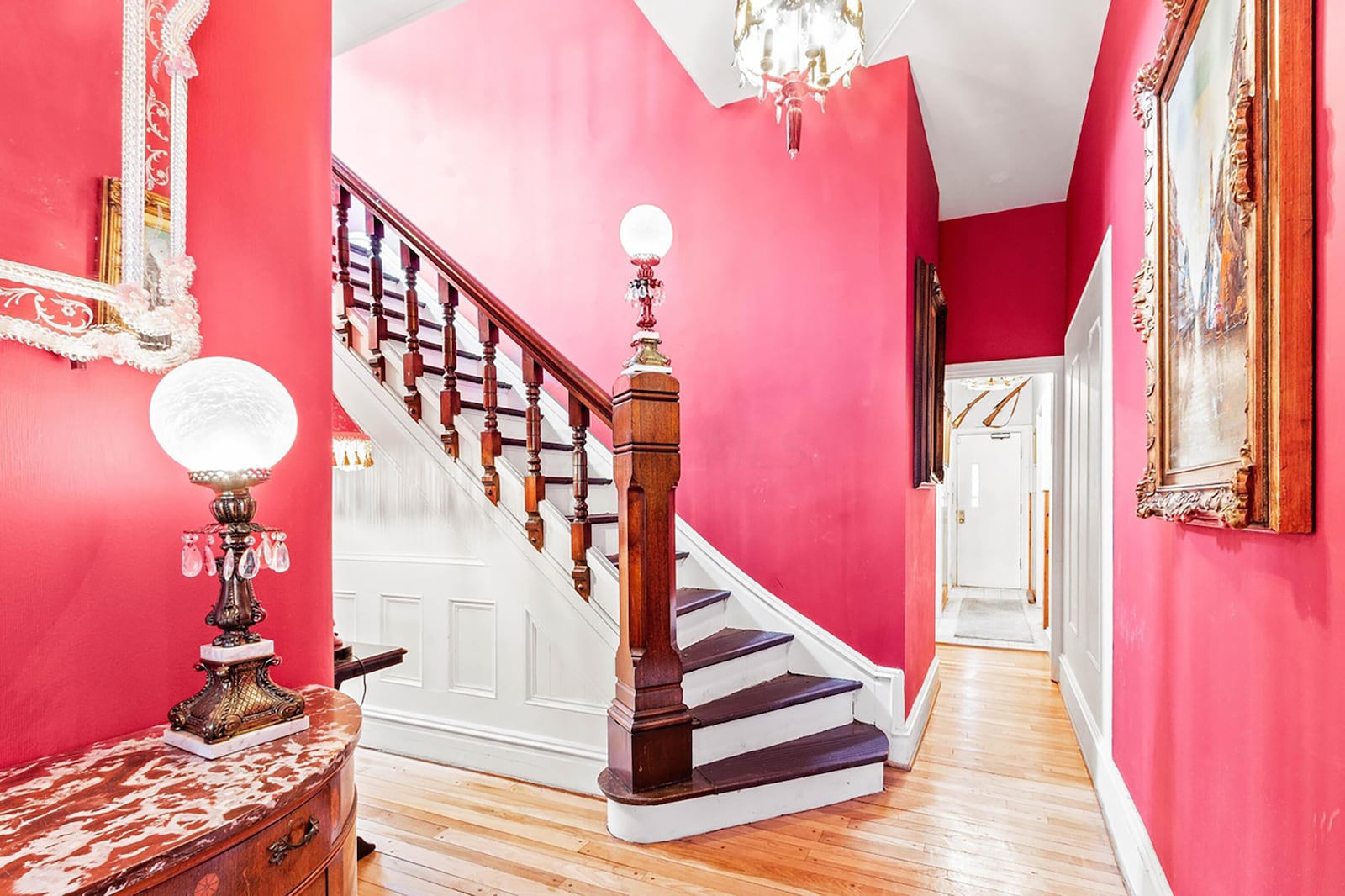 The long entryway has hardwood flooring and a wood staircase leading from the first to second floors.