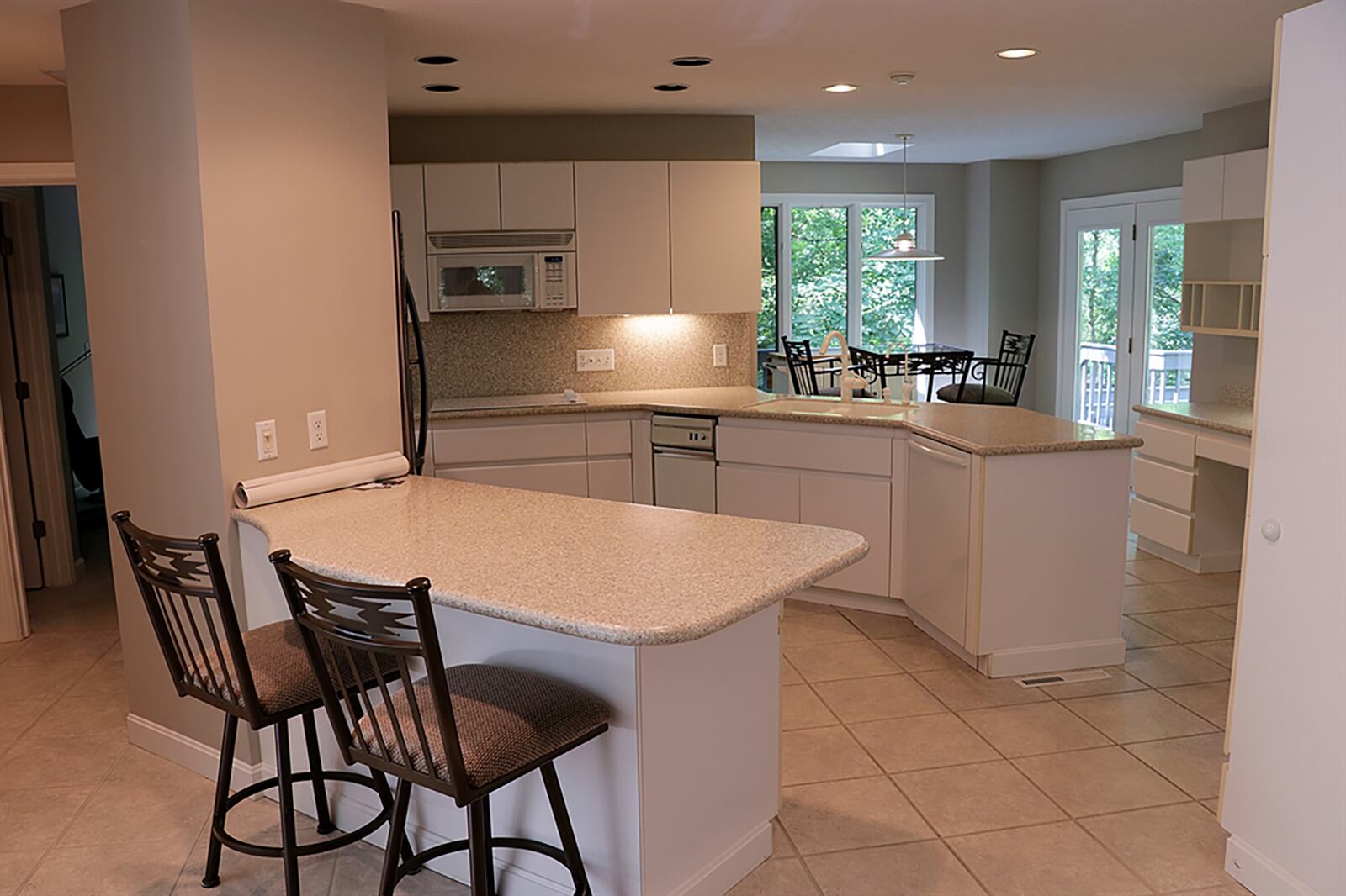 Two peninsula countertops give the kitchen a U-shaped design as one counter has breakfast bar seating for four while the other has the double sink and storage. Contemporary white cabinetry includes an appliance garage, a planning desk and a coffee station. CONTRIBUTED PHOTO BY KATHY TYLER