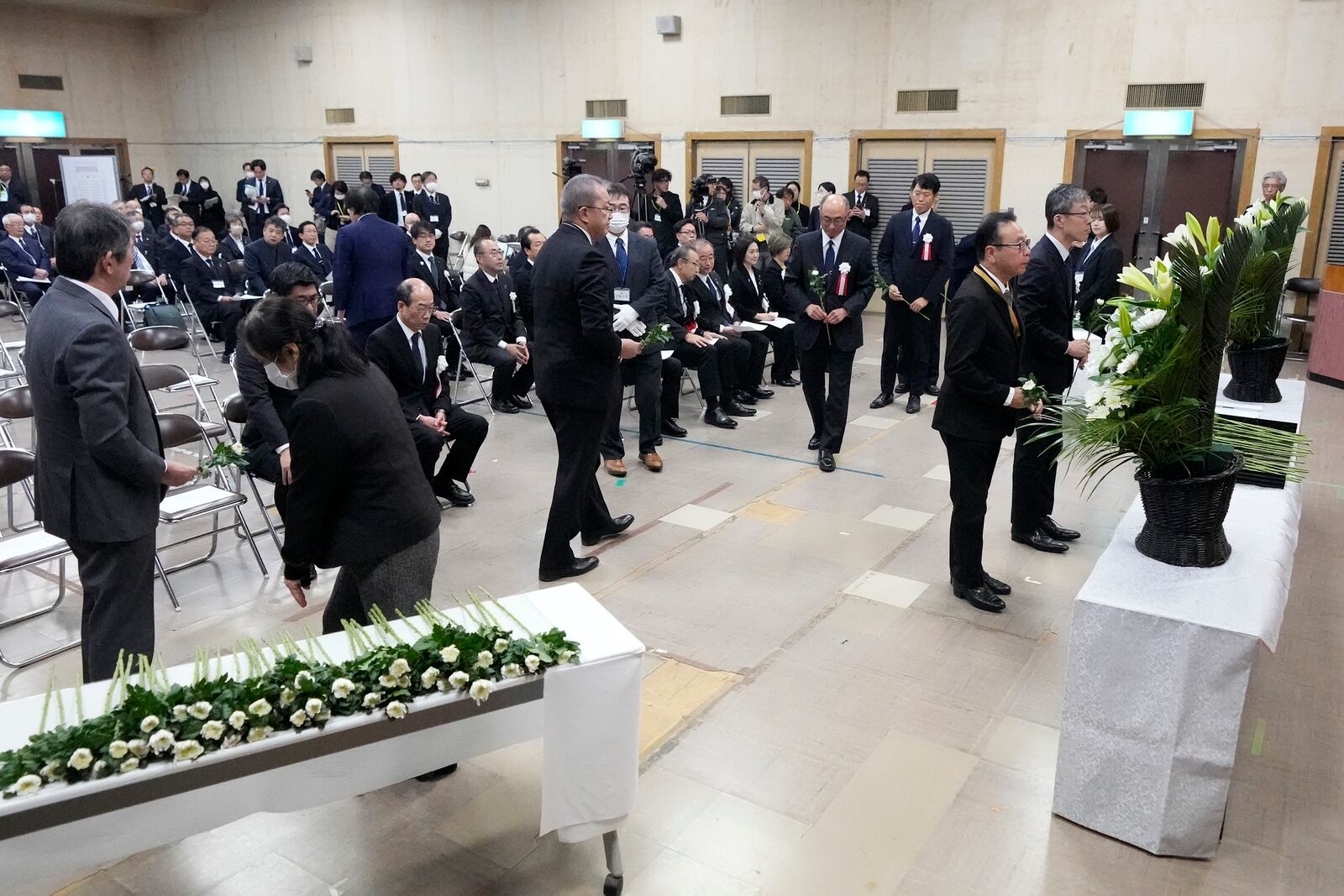 Guests offer a flower during a memorial ceremony for the Sado Island Gold Mine in Sado, Niigata prefecture, Japan, as several seats reserved for South Korean guests remained empty Sunday, Nov. 24, 2024. (AP Photo/Eugene Hoshiko)