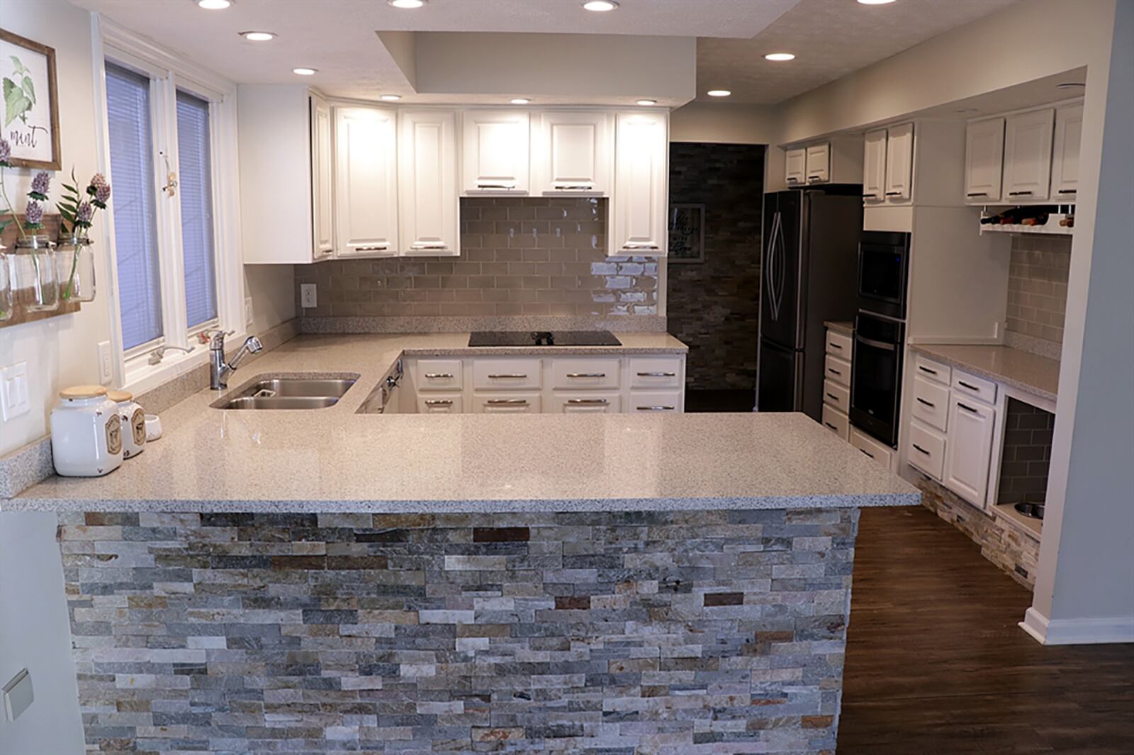 A peninsula countertop divides the kitchen from the great room and creates a breakfast bar setting. Stack-stone accents the breakfast bar and part of the kitchen, which has white cabinetry and granite countertops. CONTRIBUTED PHOTO BY KATHY TYLER