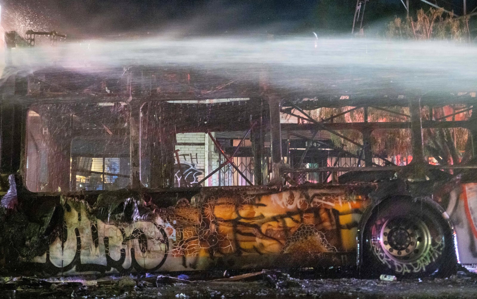 Firefighters douse water on a bus that was set on fire at Sunset and Echo Park after people gathered on the streets after the Los Angeles Dodgers defeated the New York Yankees to win the baseball World Series early Thursday, Oct. 31, 2024, in Los Angeles. (AP Photo/Ethan Swope)