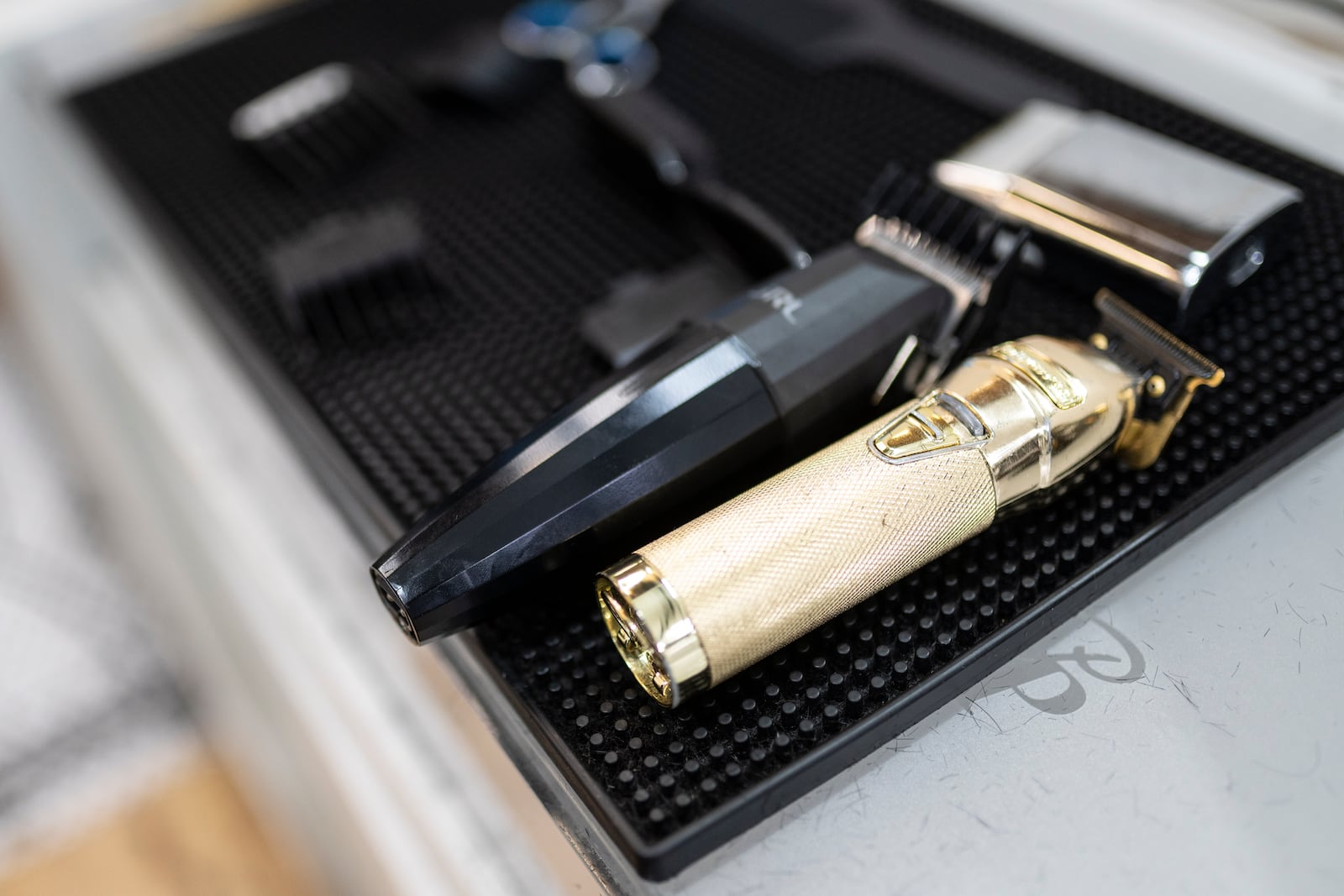 A gold-plated buzzer rests on workstations as barbers tend to their clients at 12 Pell, a local barbershop in Manhattan's Chinatown, Thursday, Jan. 25, 2024, in New York. (AP Photo/John Minchillo)