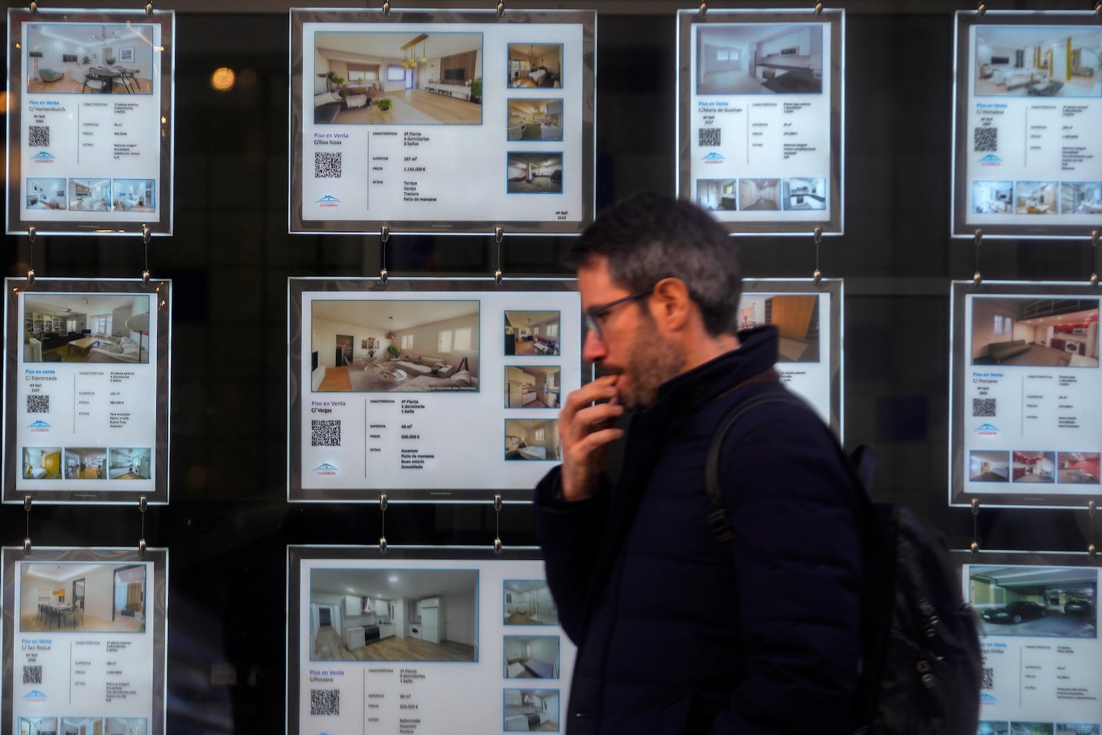 A man walks past an estate agent office advertising apartments in Madrid, Spain, Tuesday, Jan. 14, 2025. (AP Photo/Paul White)