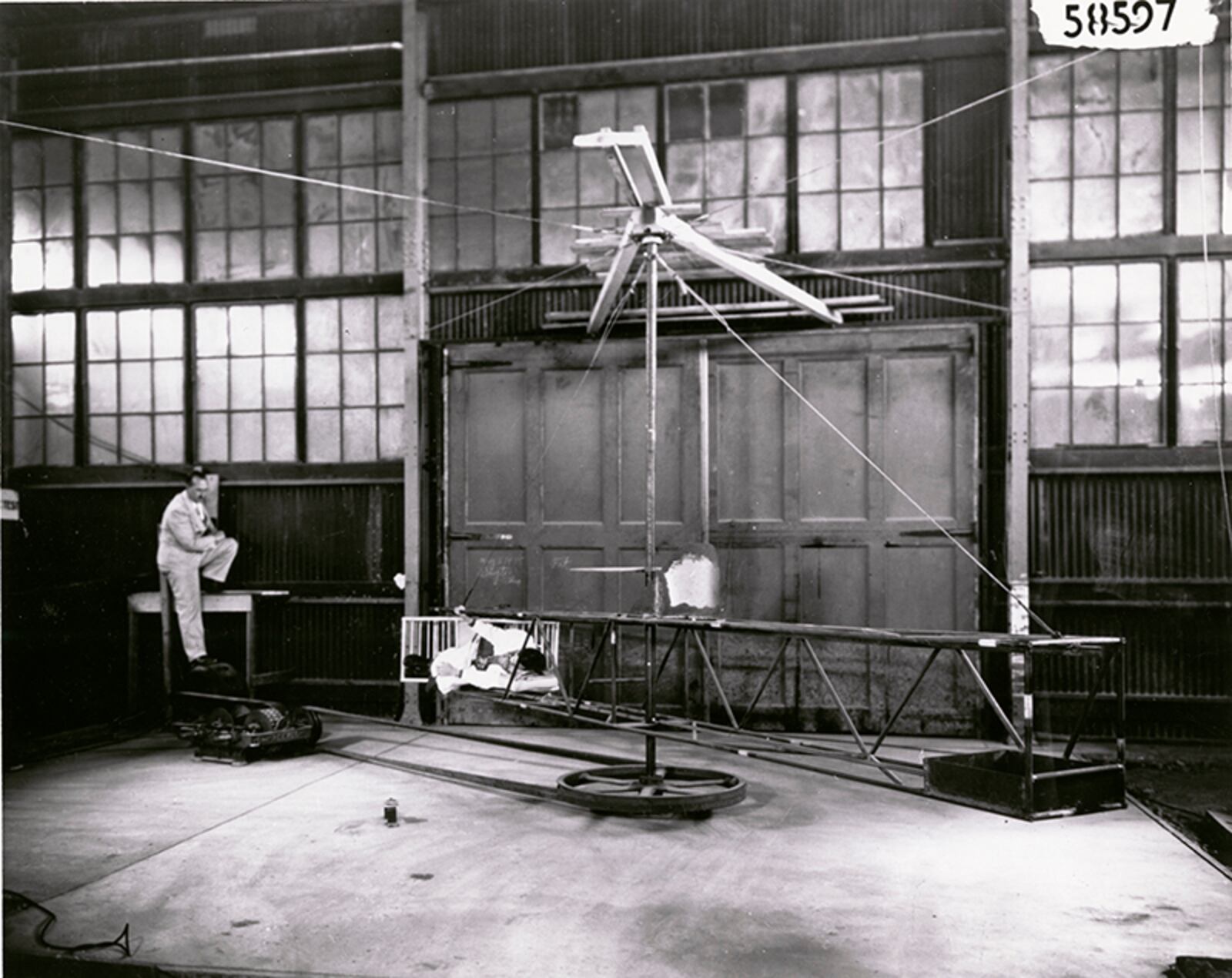 According to the caption on the back of this photograph, this human centrifuge was the first built in the United States. The centrifuge was located in a balloon hangar on the flight line of Wright Field, and was constructed by Capt. Harry Armstrong and Dr. John W. Heim. Human centrifuges were designed to test the resistance of the human body to g-forces, a force commonly felt by pilots. Armstrong, who is pictured sitting on the table to the left, eventually became one of the leading minds in aerospace medicine, and would also serve as Surgeon General of the United States. Interestingly, the centrifuge in this picture has the human subject lying on his or her side. Today’s centrifuges generally have the subject seated in an upright position. DAYTON DAILY NEWS ARCHIVES