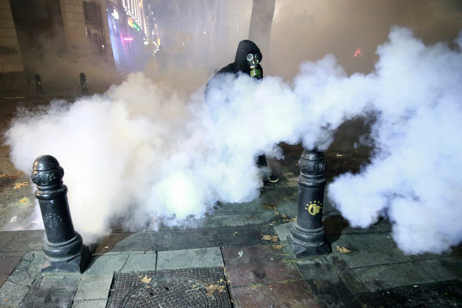 A demonstrator walks through a cloud of tear gas during a rally to protest against the government's decision to suspend negotiations on joining the European Union in Tbilisi, Georgia, early Wednesday, Dec. 4, 2024. (AP Photo/Zurab Tsertsvadze)