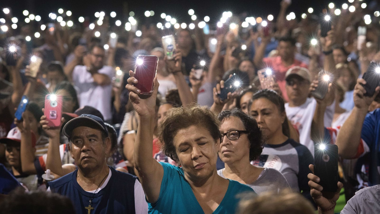 Mourners hold up their cellphones during an Aug. 4, 2019, candlelight vigil for the victims of a mass shooting at an El Paso, Texas, Walmart the day before. The 23rd victim of the shooting, Guillermo “Memo” Garcia, died Saturday, April 25, 2020, nearly nine months after the massacre. (Mark Ralston/AFP via Getty Images)