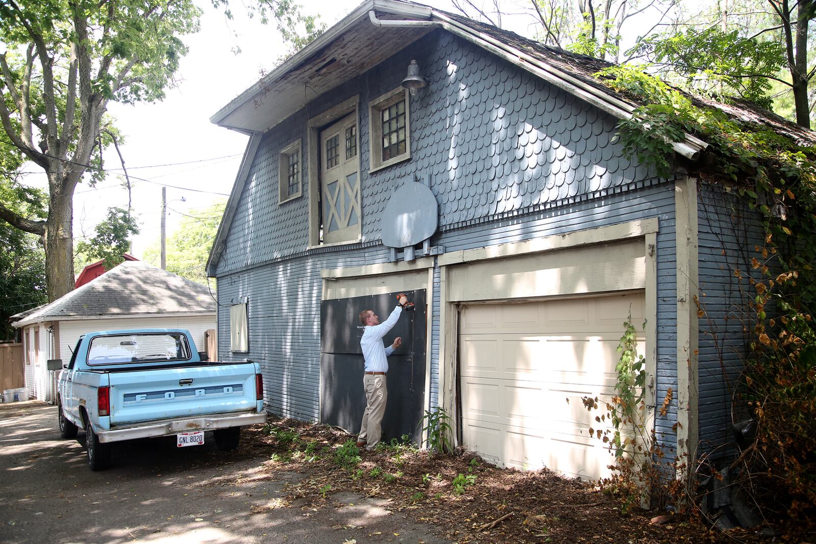 Chris Lewis, the new owner of the historic former home of Gov. James M. Cox, opens the boarded up carriage house. LISA POWELL / STAFF