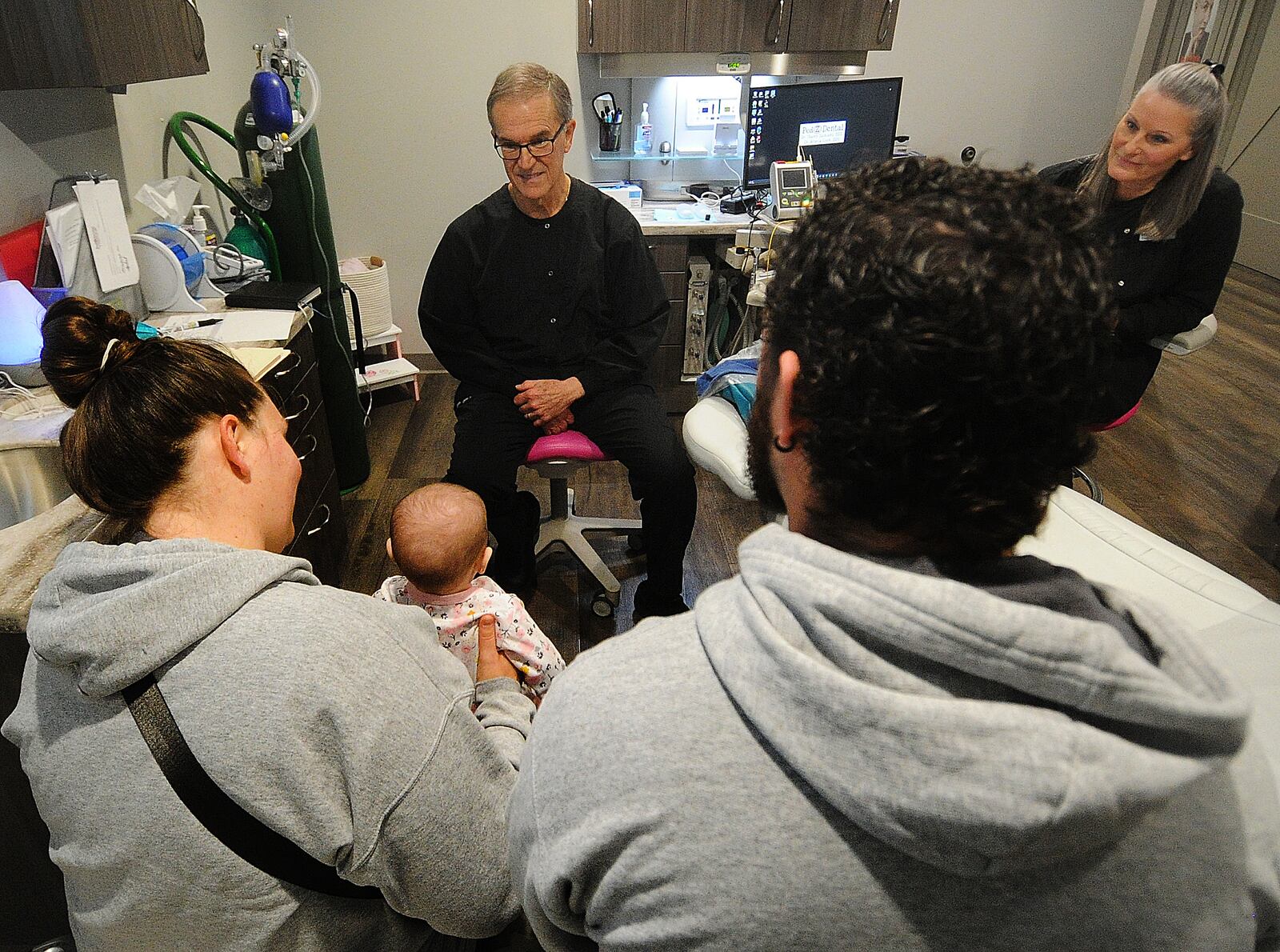 Dr. Gregory Notestine, left, with dental assistant Tammy Brewer talks to a patient's parents Friday, Jan. 26, 2024 at PedZ Dental located at 5671 Far Hills Ave. MARSHALL GORBY\STAFF