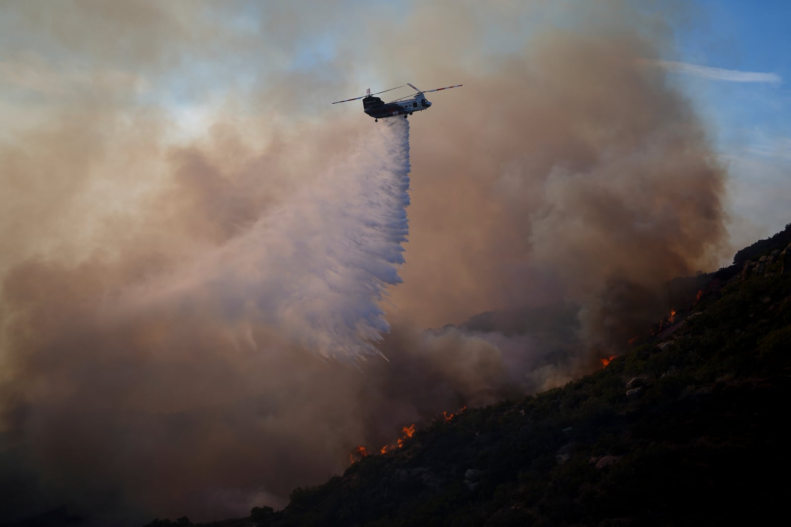 Water is dropped by helicopter onto the Franklin Fire, Tuesday, Dec. 10, 2024, in Malibu, Calif. (AP Photo/Eric Thayer)