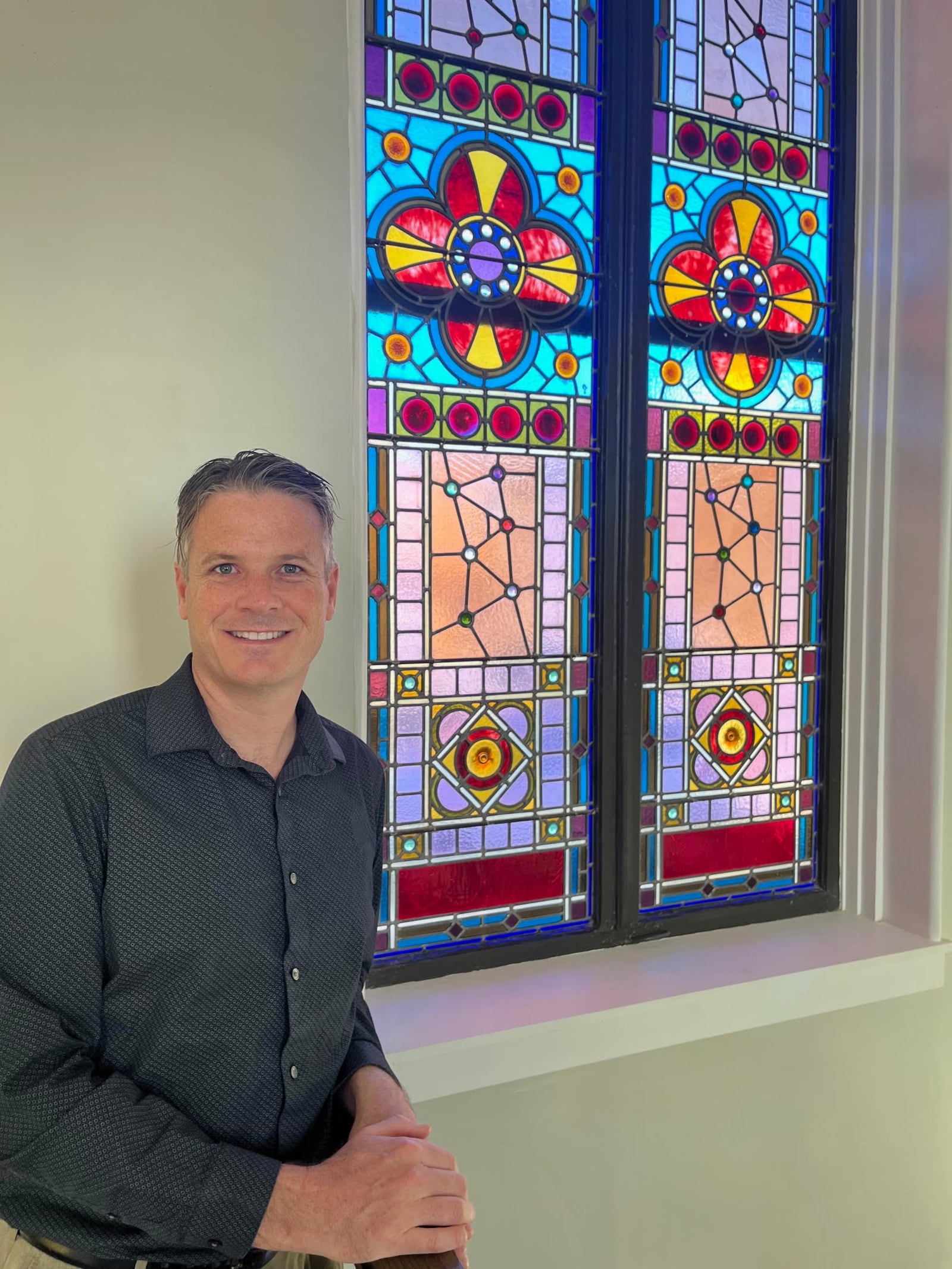 Scott Strayer, owner of The 1833, a new wedding and event venue in Troy, stands next to some of the building’s early 1900s-era stained glass windows that have been redone. CONTRIBUTED PHOTO