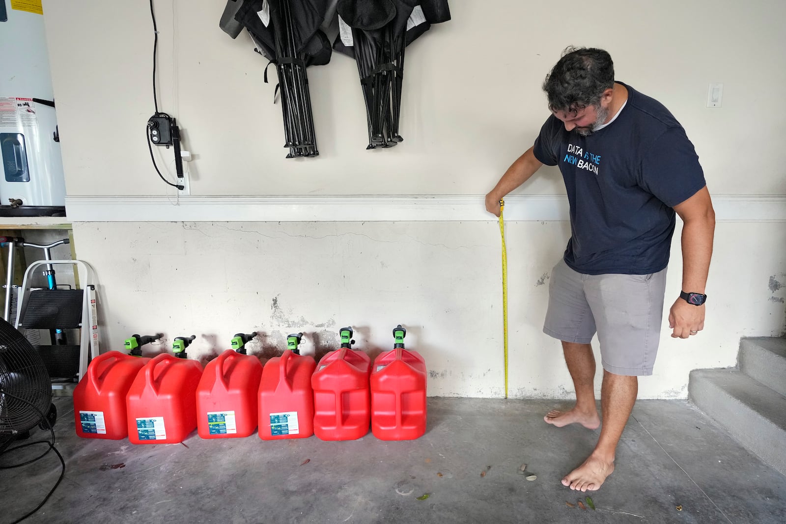 Chris Sundar measures the depth of floodwaters from Hurricane Milton in his garage Sunday, Oct. 13, 2024, in Tampa, Fla. (AP Photo/Chris O'Meara)