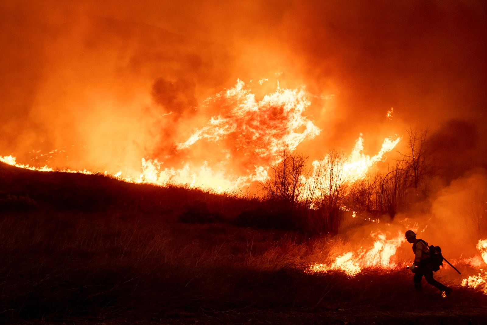 A firefighter sets a backburn in front of the advancing Kenneth Fire in the West Hills section of Los Angeles, Thursday, Jan. 9, 2025. (AP Photo/Ethan Swope)