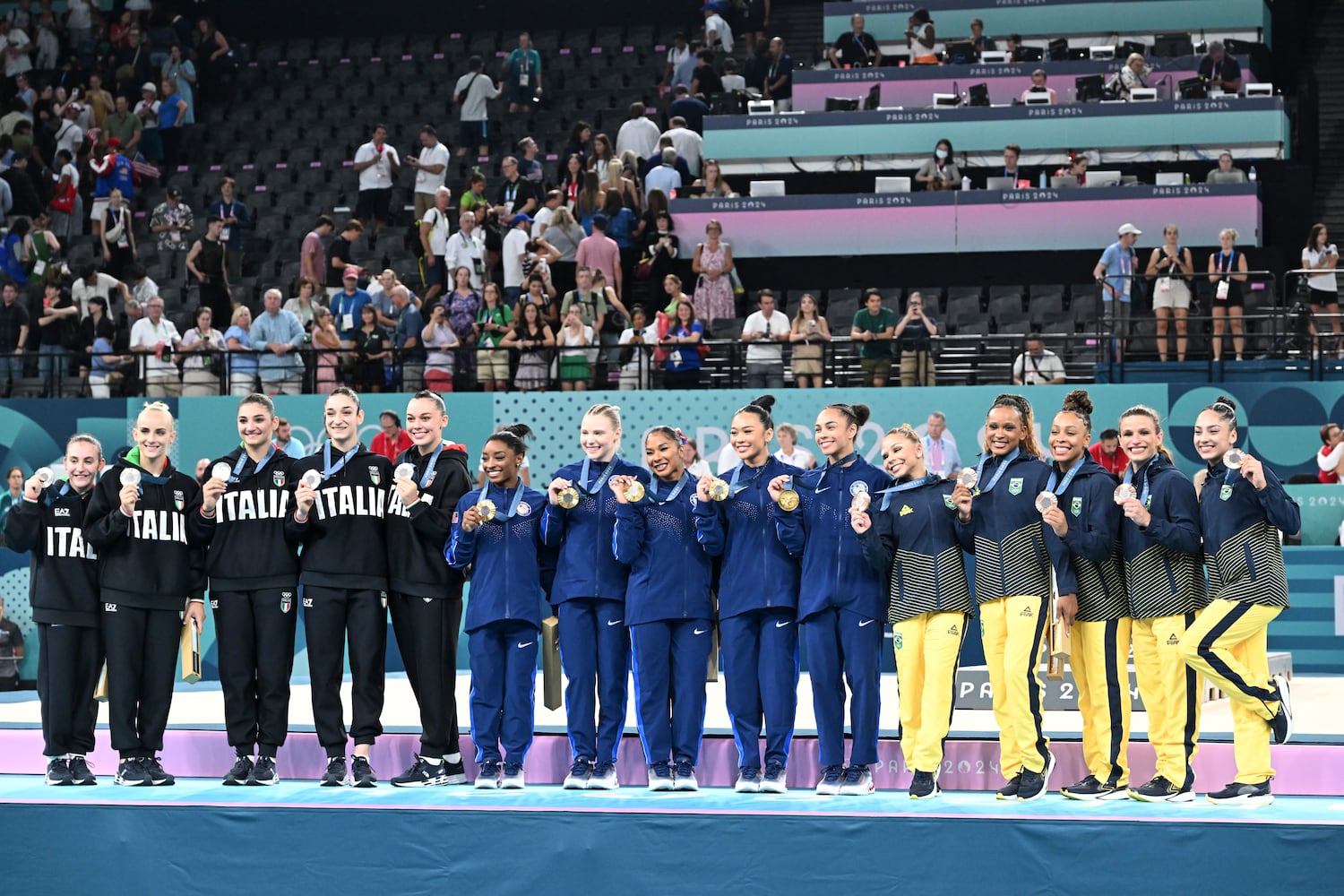 
                        From left: The silver medal Italian team, gold medal U.S. team and bronze medal Brazilian team at the medal ceremony for the women's artistic gymnastics team finals at the 2024 Summer Olympics at Bercy Arena in Paris, on Tuesday, July 30, 2024. (James Hill/The New York Times)
                      