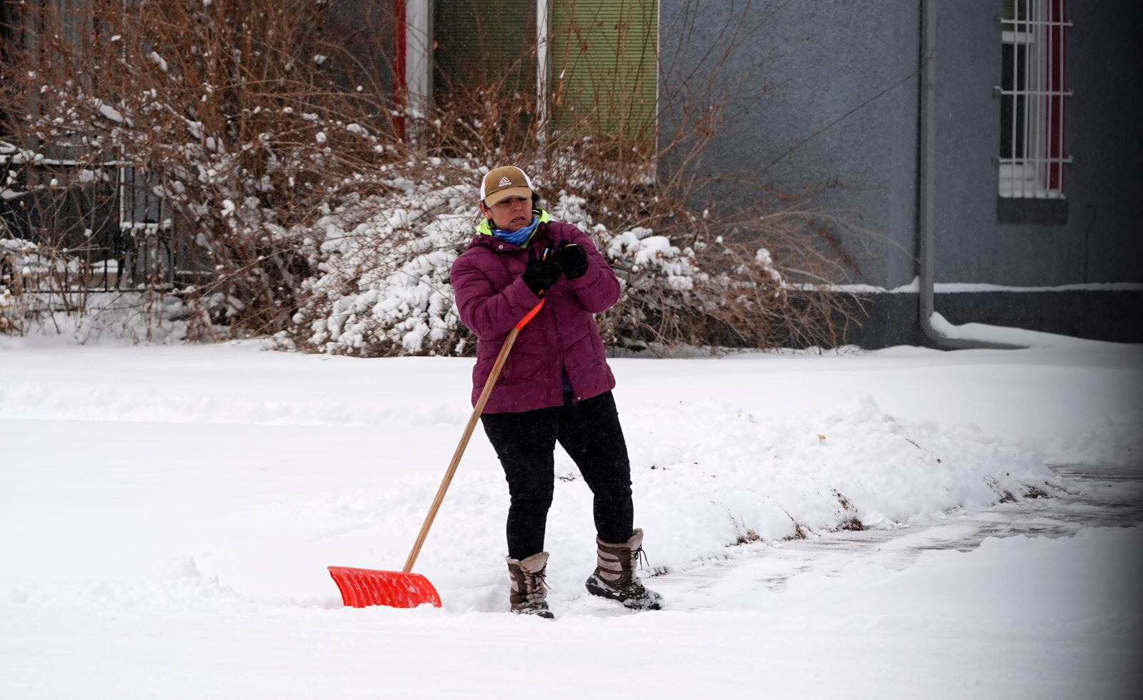 A person takes a break from clearing a walkway along Bannock Street as a winter storm sweeps over the intermountain West, plunging temperatures into the single digits and bringing along a light snow in its wake Saturday, Jan. 18, 2025, in Denver. (AP Photo/David Zalubowski)