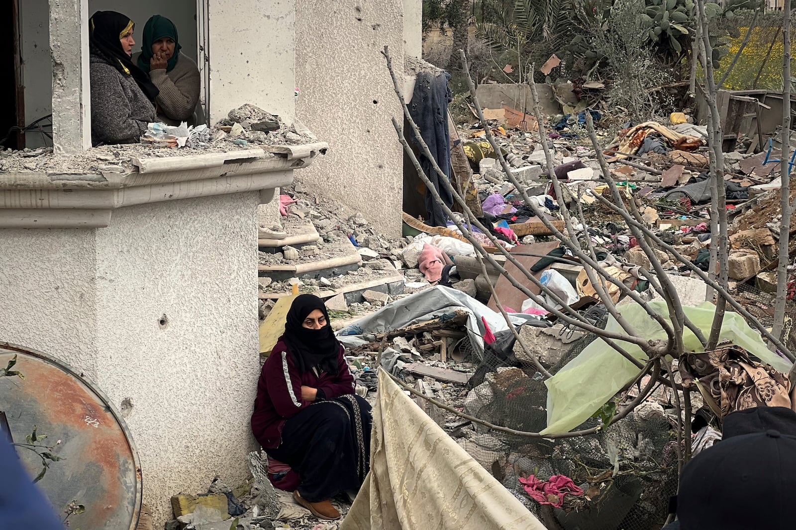 Neighbours watch as volunteers and rescue workers search for survivors among the rubble of a building hit by an Israeli army airstrike in Khan Younis, southern Gaza Strip, Thursday, March 20, 2025. (AP Photo/Mariam Dagga)