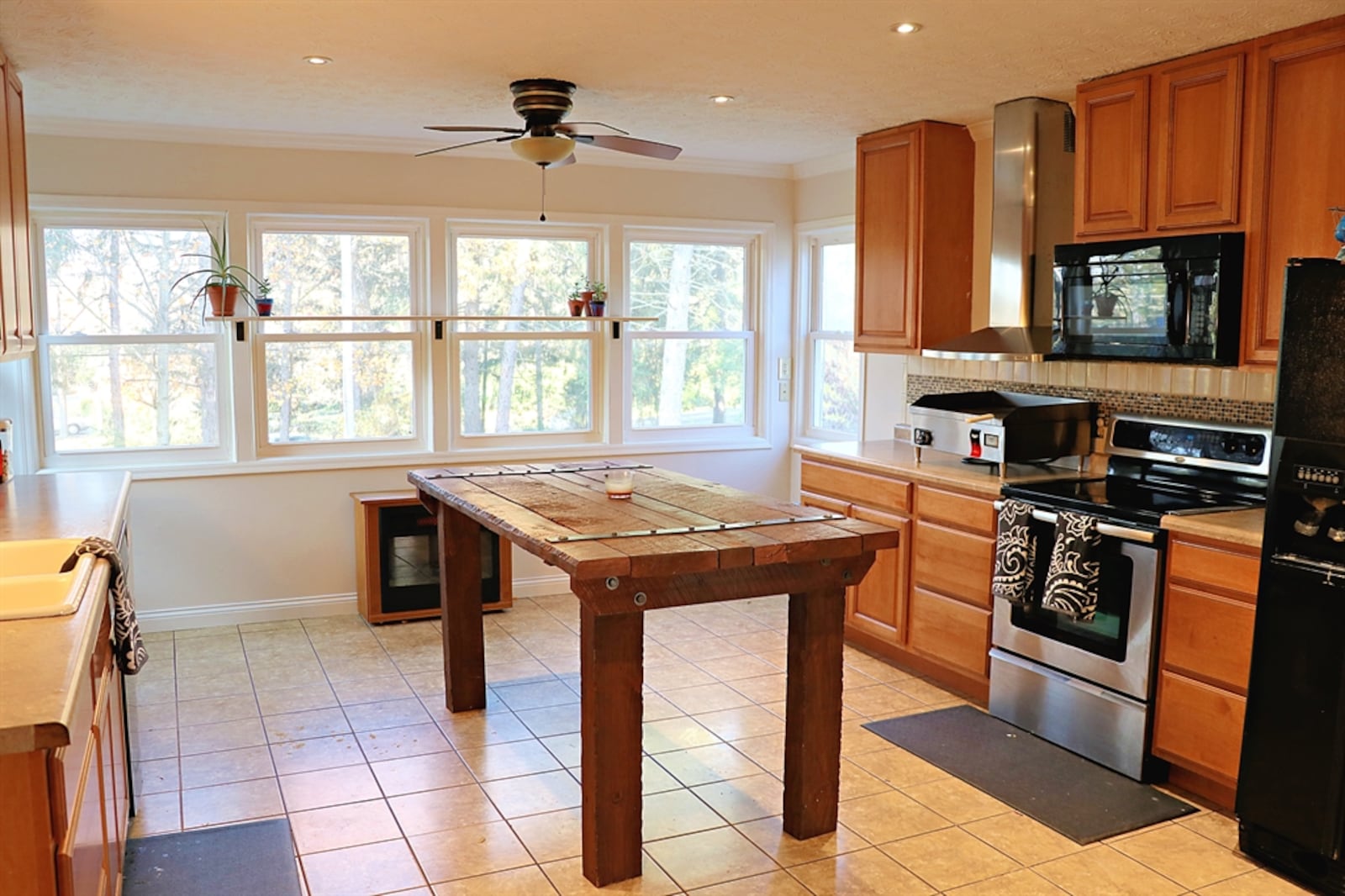 Six windows fill the kitchen with natural light and surround a breakfast room area. Three walls have light maple cabinetry. 