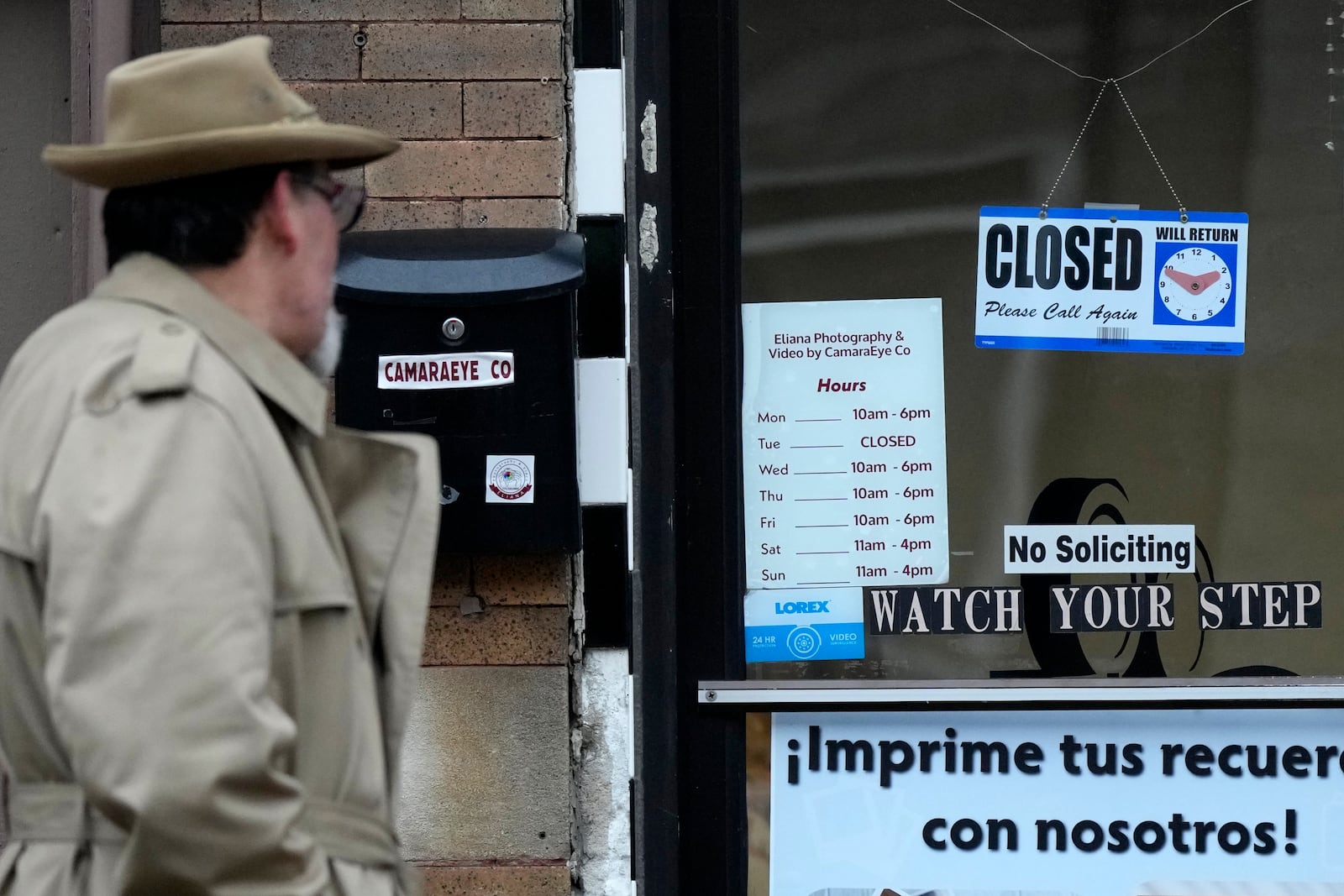 A pedestrian looks at signs displayed on the front door of a store in the Little Village neighborhood of Chicago, Monday, Feb. 3, 2025. (AP Photo/Nam Y. Huh)