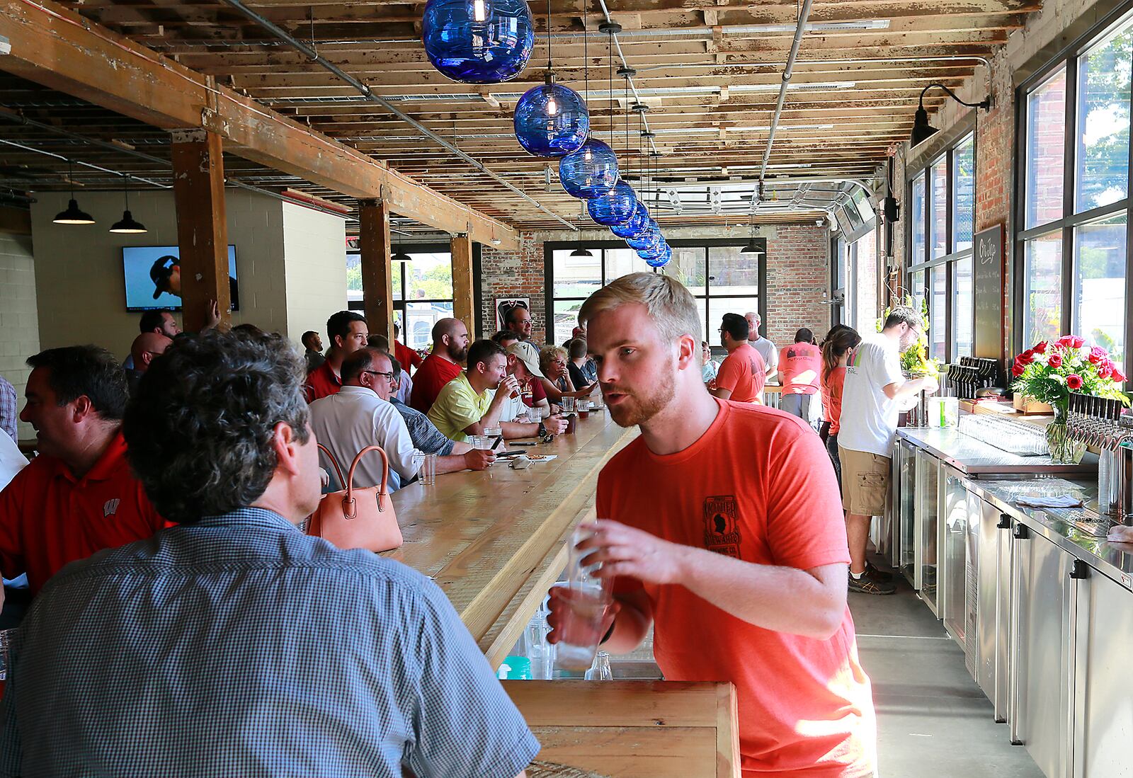 Workers at Mother Stewarts Brewing Co. wait on a crowd of customers . Bill Lackey/Staff