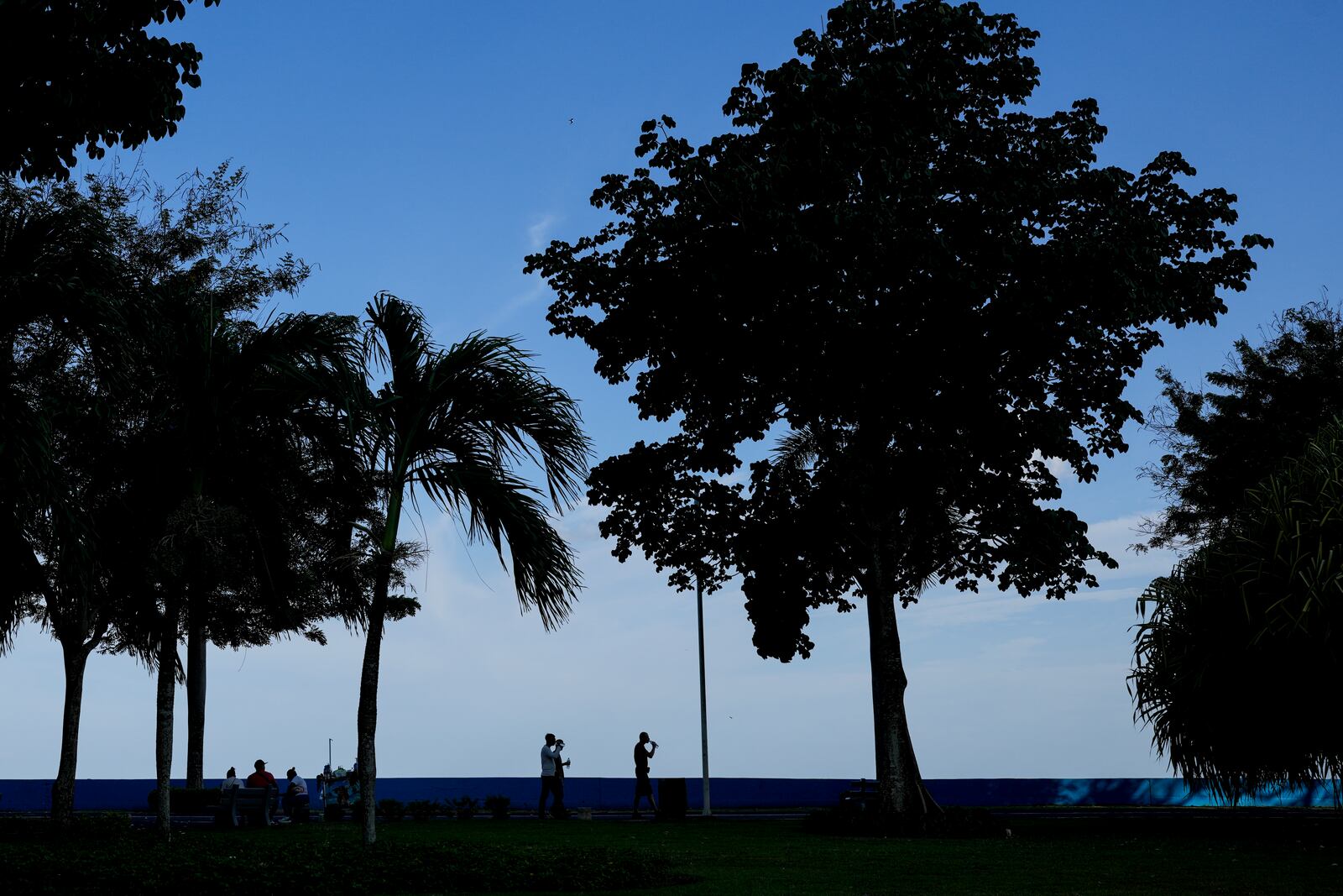 Migrants from Afghanistan and Russia, who were deported from the U.S., walk along the waterfront in Panama City, Tuesday, March 18, 2025, after visiting the Canadian Embassy in hopes of applying for asylum. (AP Photo/Matias Delacroix)