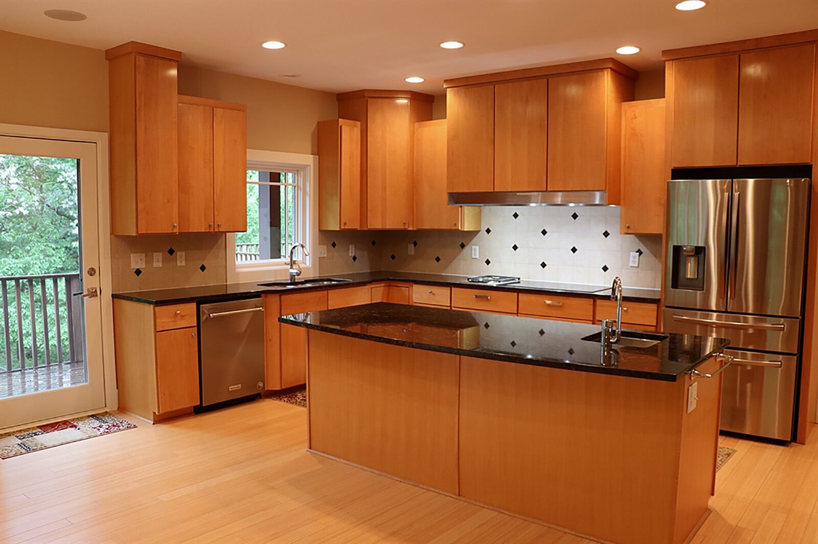 Maple kitchen cabinetry with dark granite countertops provide plenty of storage and work space. A window is above the sink and an island has a vegetable sink. The cooktop has a glass-top and a gas burner. The kitchen continues into an extended butler’s pantry. CONTRIBUTED PHOTO BY KATHY TYLER