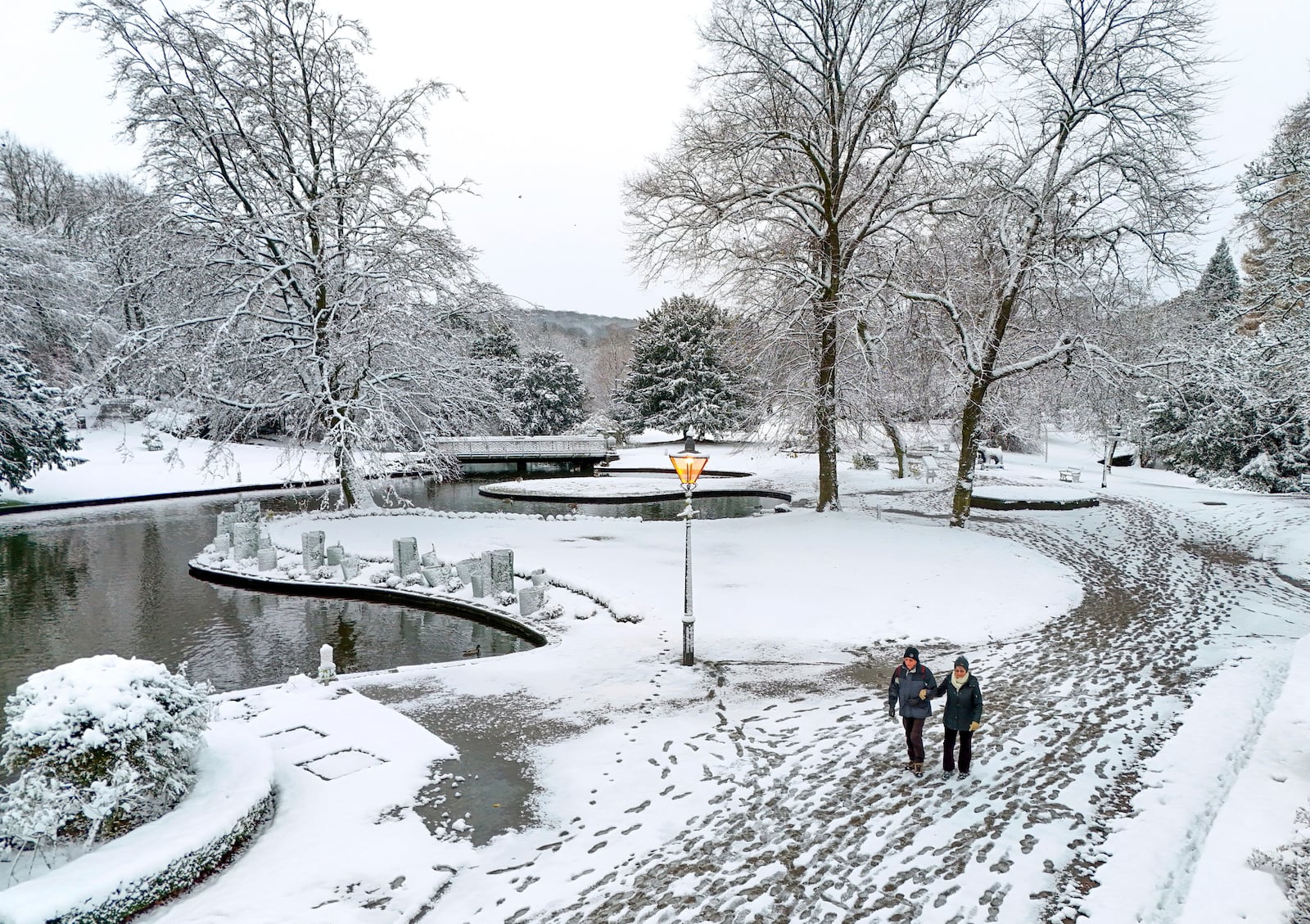 People walk through a park covered in snow after the overnight snowfall in Buxton, Derbyshire, Britain, Tuesday Nov. 19, 2024. (Peter Byrne/PA via AP)