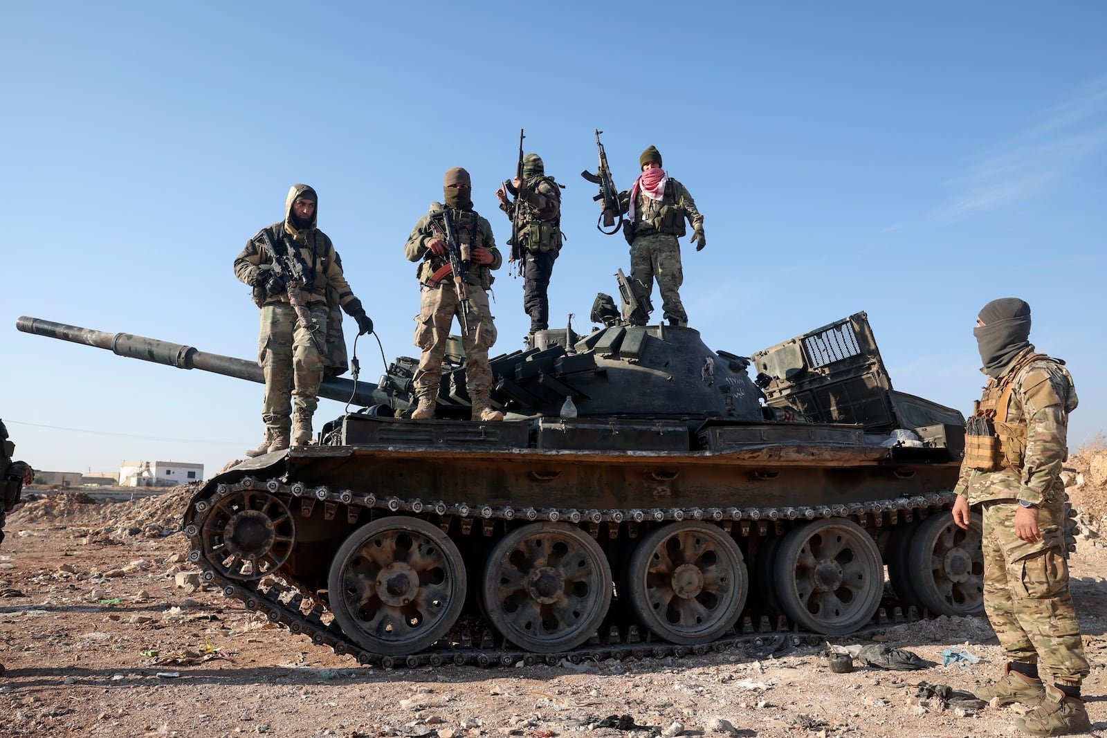 Syrian opposition fighters stand atop a seized military armored vehicle on the outskirts of Hama, Syria, Tuesday, Dec. 3, 2024. (AP Photo/Ghaith Alsayed)