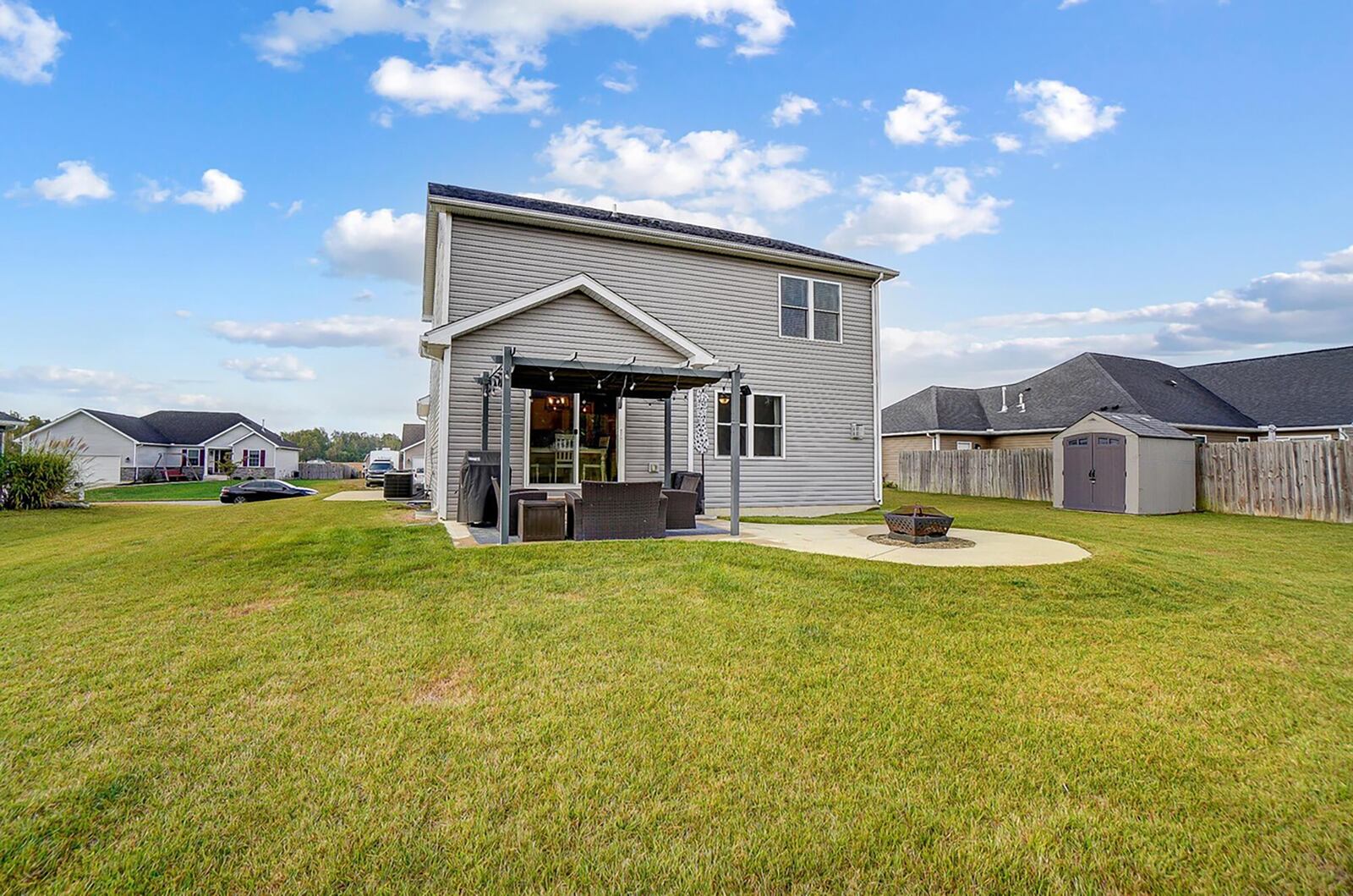 The rear of the home has a concrete patio with firepit extension and wood pergola.