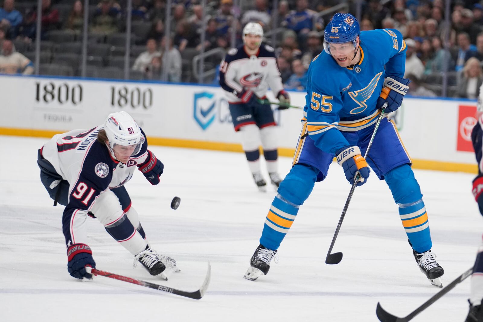 St. Louis Blues' Colton Parayko (55) and Columbus Blue Jackets' Kent Johnson (91) chase after a loose puck during the second period of an NHL hockey game Saturday, Jan. 11, 2025, in St. Louis. (AP Photo/Jeff Roberson)