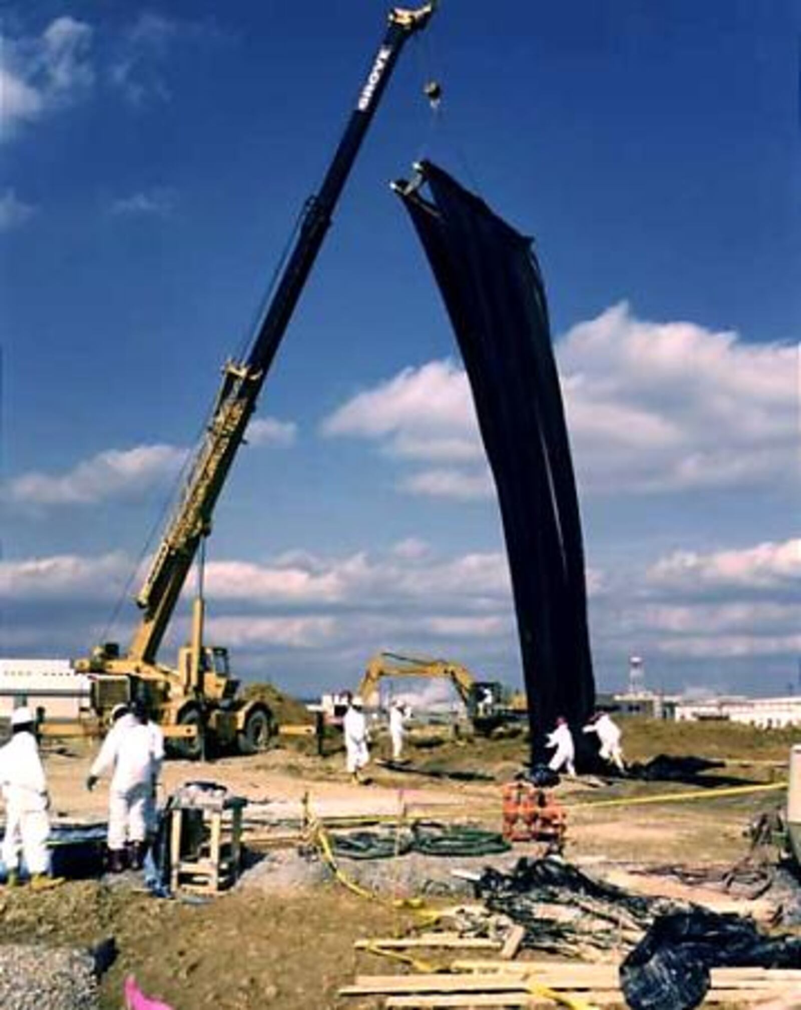 Workers lower a liner into a trench being built to intercept contaminated groundwater so it can be treated at the Portsmouth Gaseous Diffusion Plant site. The trench is beside a landfill over the large groundwater plume on the reservation's southern edge.