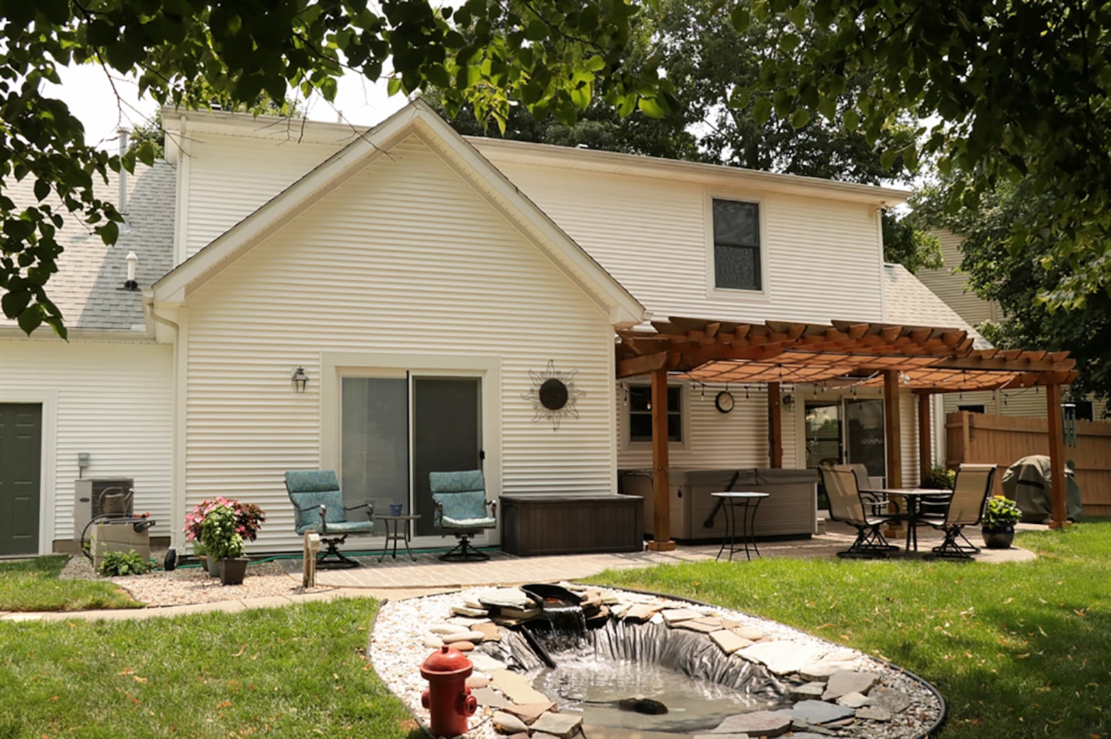 A wooden privacy fence surrounds the back yard with tailored gardens and a garden shed. Decorative stepping stones lead from the driveway gate to a stone patio, part of which is covered by a pergola. A water feature is just off the sun patio and there is electric and space for a hot tub. CONTRIBUTED PHOTO BY KATHY TYLER