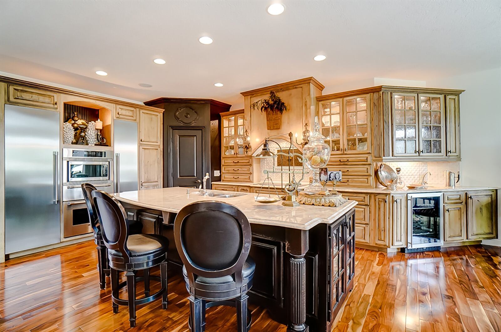 Marble countertops in the kitchen cover knotty-alder cabinetry, which includes many drawers and lighted glass-door hanging cabinets. An island has a double sink, glass display case on each end and breakfast bar seating for four. CONTRIBUTED PHOTO