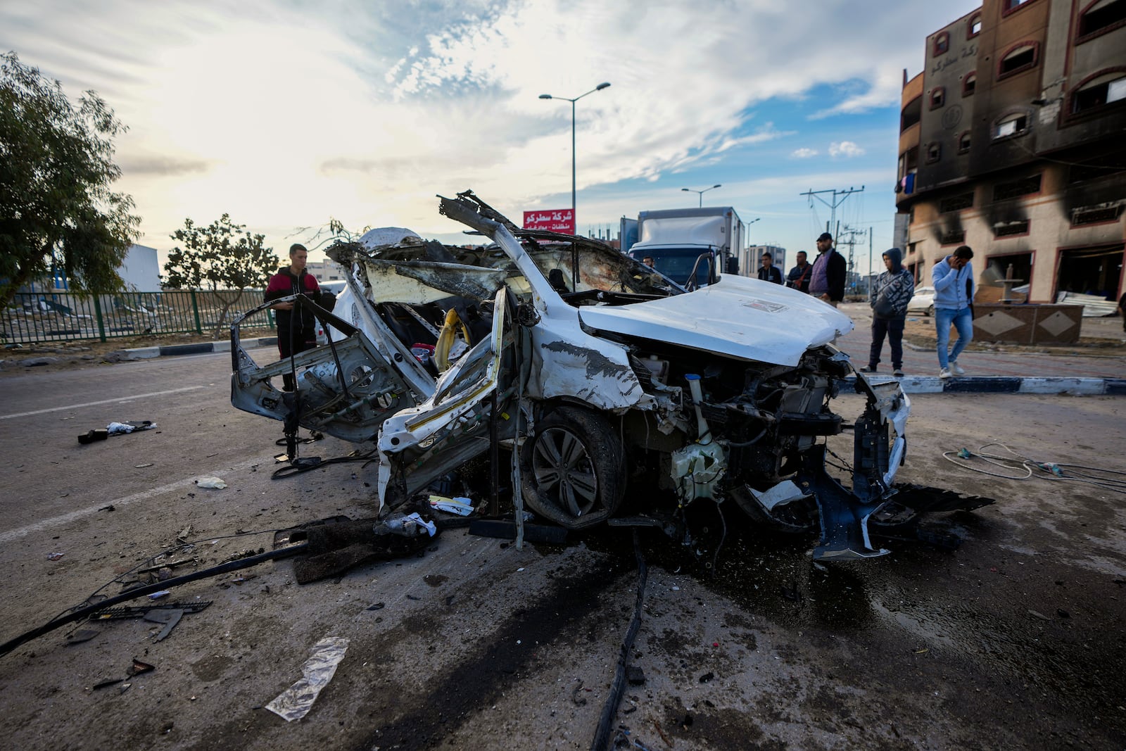 Palestinians inspect a car targeted in an overnight Israeli airstrike that killed its occupants in the town of Khan Younis, southern Gaza Strip, Saturday, Jan. 4, 2025. (AP Photo/Abdel Kareem Hana)