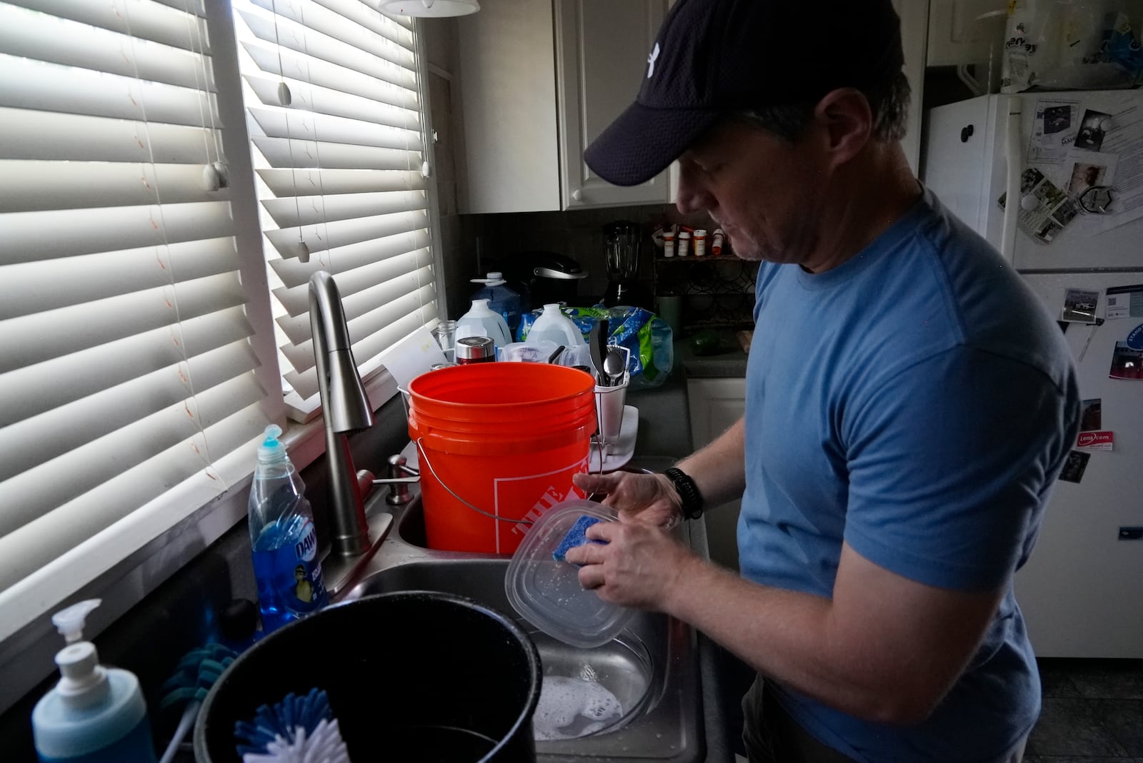 FILE - Travis Edwards captures excess water while cleaning dishes on Oct. 3, 2024, in Asheville, N.C. (AP Photo/Brittany Peterson, File)