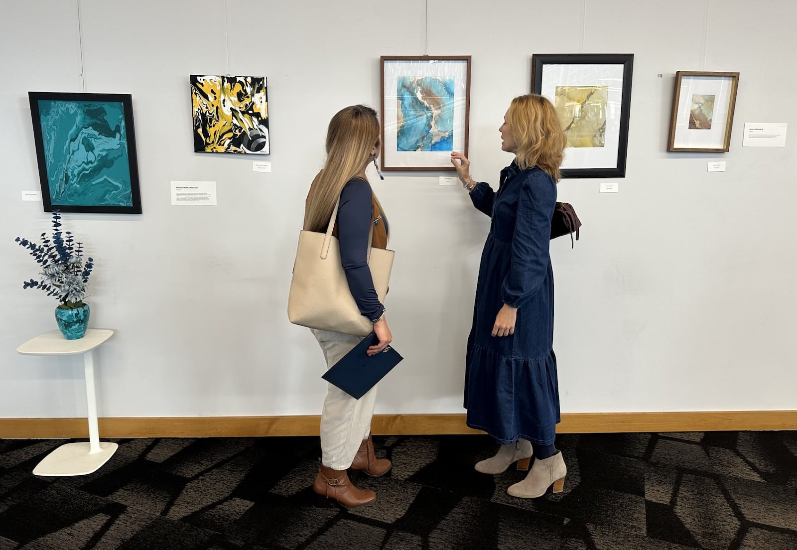 Artists Samaneh Faramarzi (Iran) and Yuliia Goncharuk (Ukraine) are seen in front of Yuliia's paintings at the downtown Dayton Metro Library. CONTRIBUTED