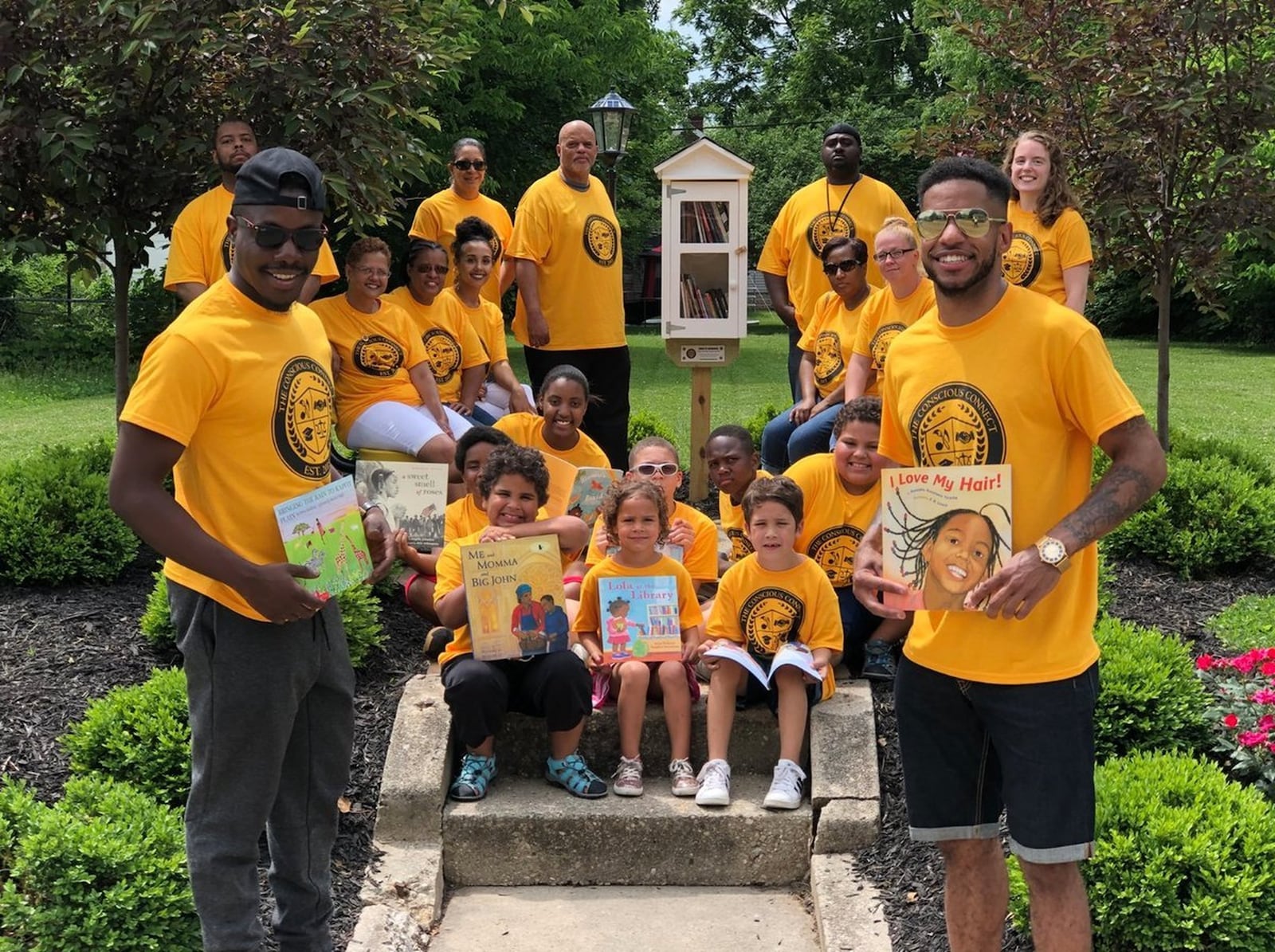 The co-founders of The Conscious Connect, Inc. Karlos L. Marshall and Moses B. Mbeseha stand with children and community members at a reading park they created on Woodward Avenue in Springfield. CONTRIBUTED.