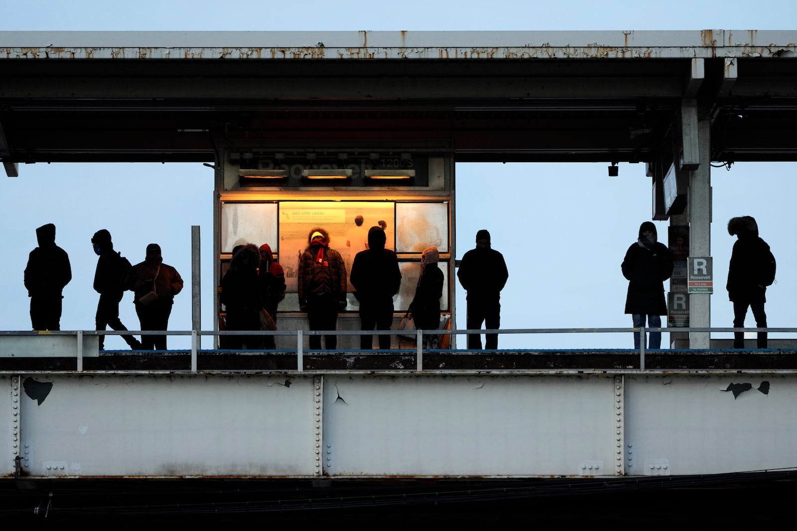 Commuters wait under a warming light for a Chicago Transit Authority train as an Arctic blast brings single-digit temperatures with wind chills below zero on Thursday, Dec. 12, 2024, in Chicago. (AP Photo/Charles Rex Arbogast)