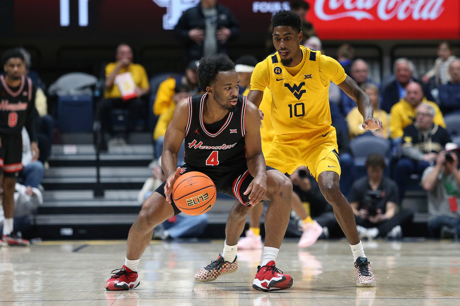 Houston guard L.J. Cryer (4) is defended by West Virginia guard Sencire Harris (10) during the first half of an NCAA college basketball game, Wednesday, Jan. 29, 2025, in Morgantown, W.Va. (AP Photo/Kathleen Batten)