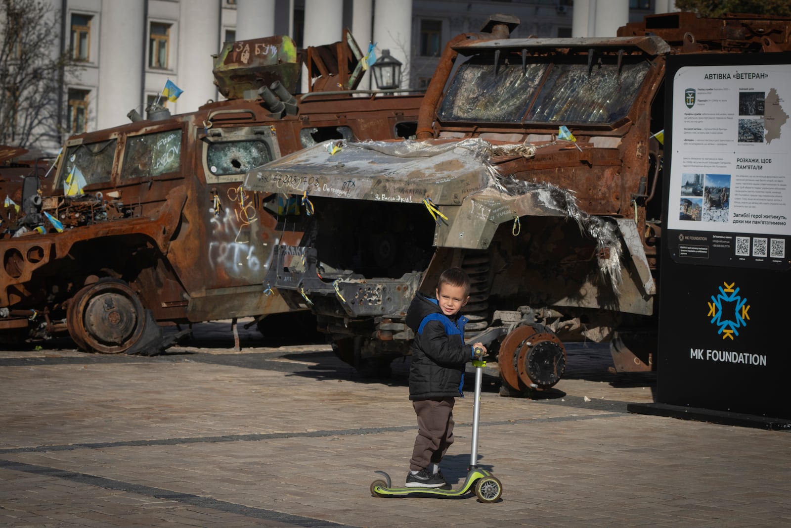 A boy rides a scooter past a display of destroyed Russian military vehicles in Mykhailivska square in central Kyiv, Ukraine, Tuesday, Oct. 22, 2024. (AP Photo/Efrem Lukatsky)