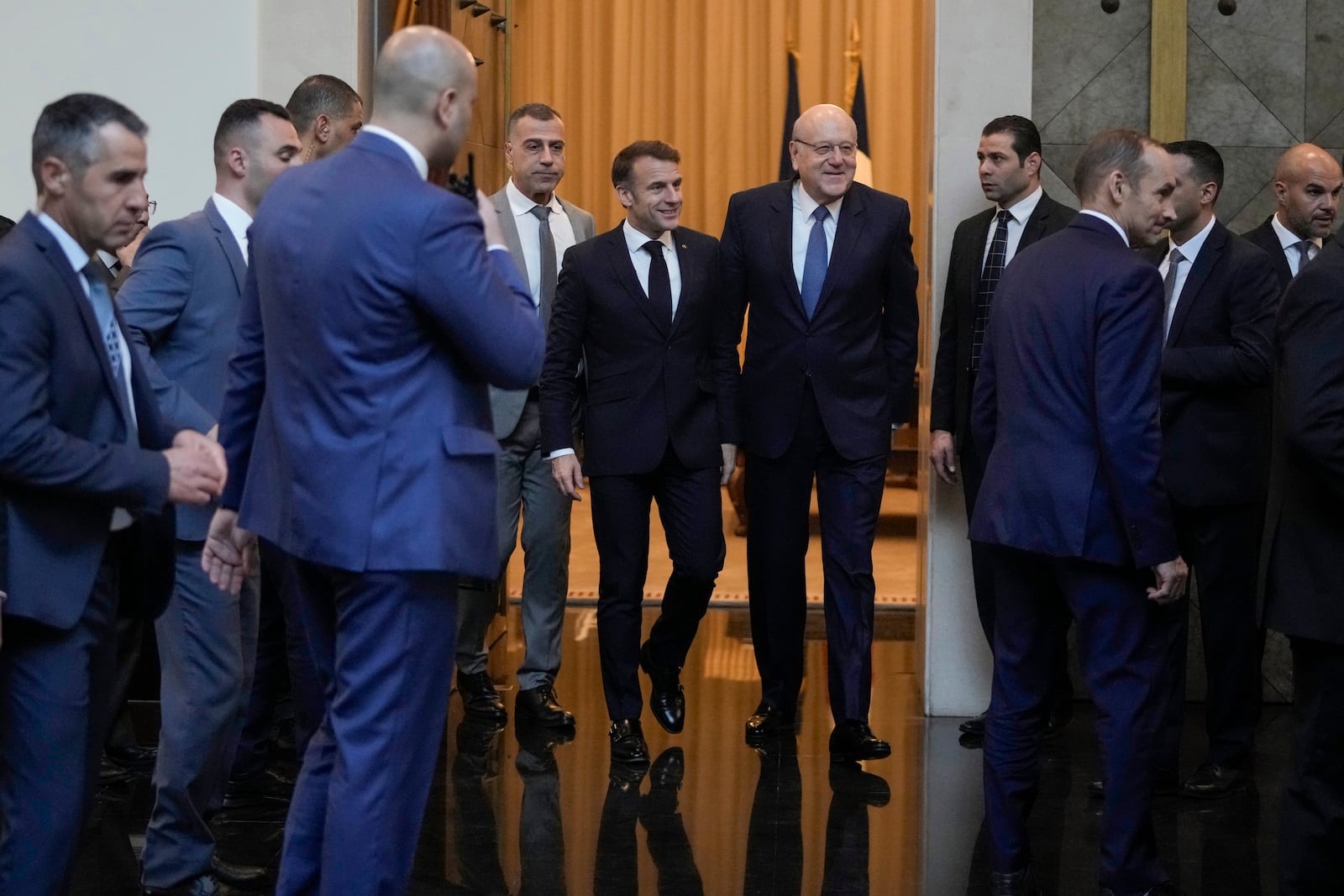 French President Emmanuel Macron, center left, walks next to Lebanese caretaker Prime Minister Najib Mikati, right, after their meeting upon his arrival at Beirut's Rafic Hariri International Airport in Beirut, Lebanon, Friday, Jan. 17, 2025. (AP Photo/Hassan Ammar)