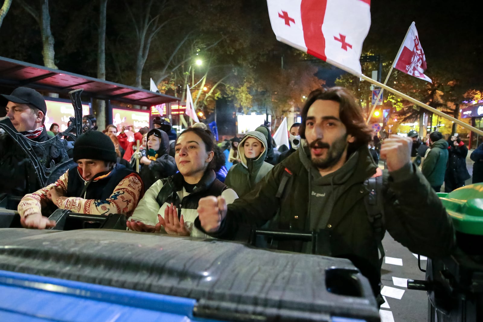 Protesters standing behind a barricade shout in a street during a rally against the results of the parliamentary elections amid allegations that the vote was rigged in Tbilisi, Georgia Tuesday, Nov. 19, 2024. (AP Photo/Zurab Tsertsvadze)