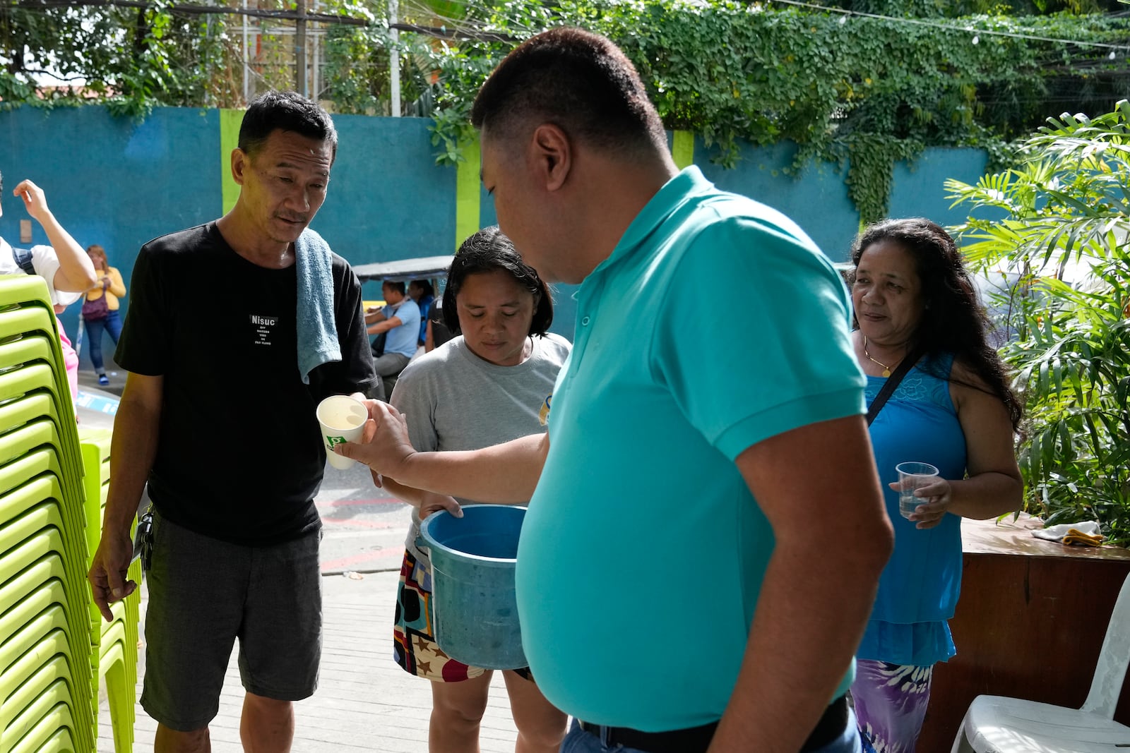 Village chief Carlito Cernal, center, inspects residents holding containers with mosquitos that they captured in Mandaluyong city, Philippines as their village started offering bounty for captured mosquitos, dead or alive, as part of an anti-dengue campaign on Wednesday, Feb. 19, 2025. (AP Photo/Aaron Favila)