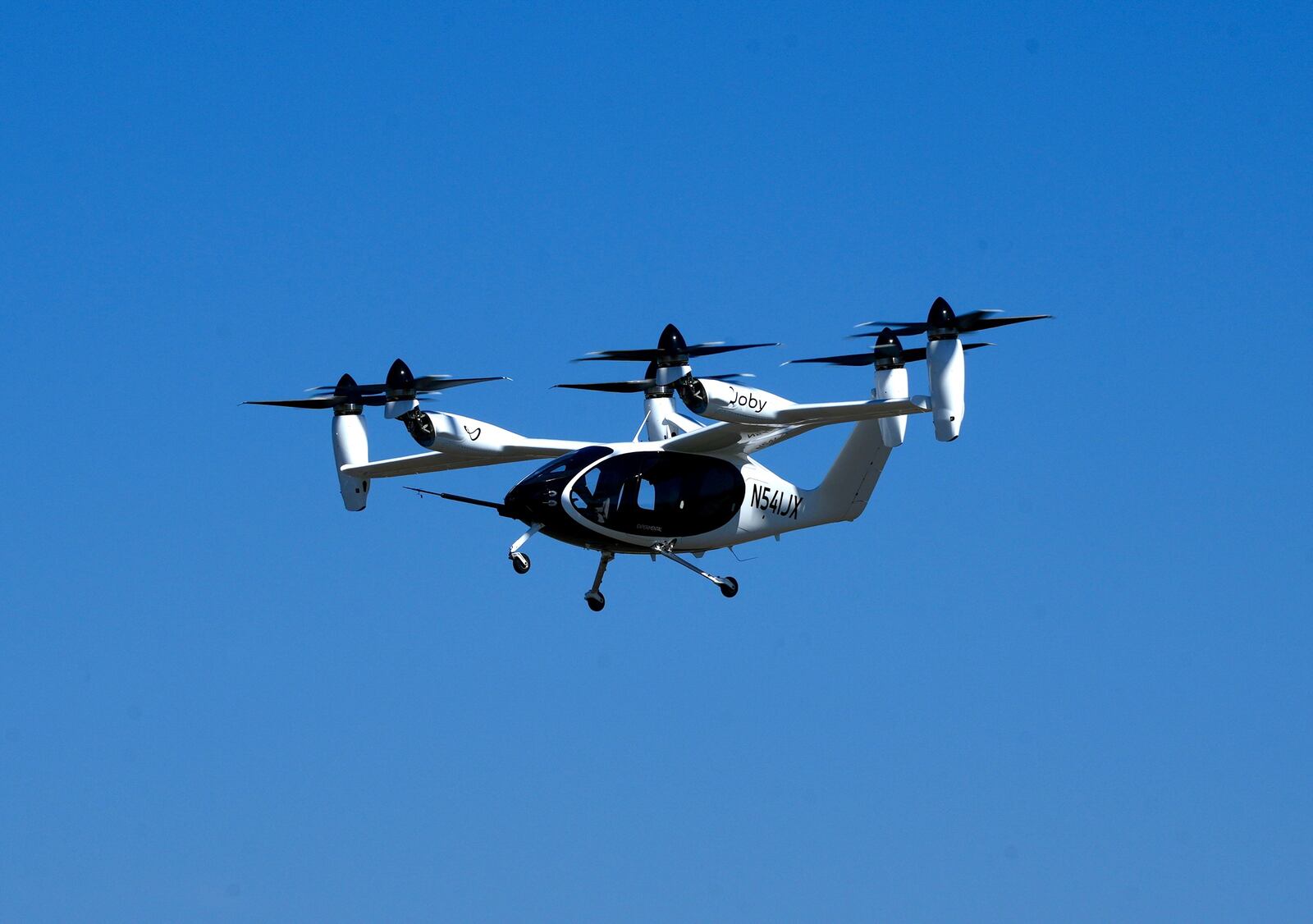 An "electric vertical take-off and landing" aircraft built by Joby Aviation flies over an airfield in Marina, Calif. on Monday, Oct. 7, 2024. (AP Photo/Terry Chea)