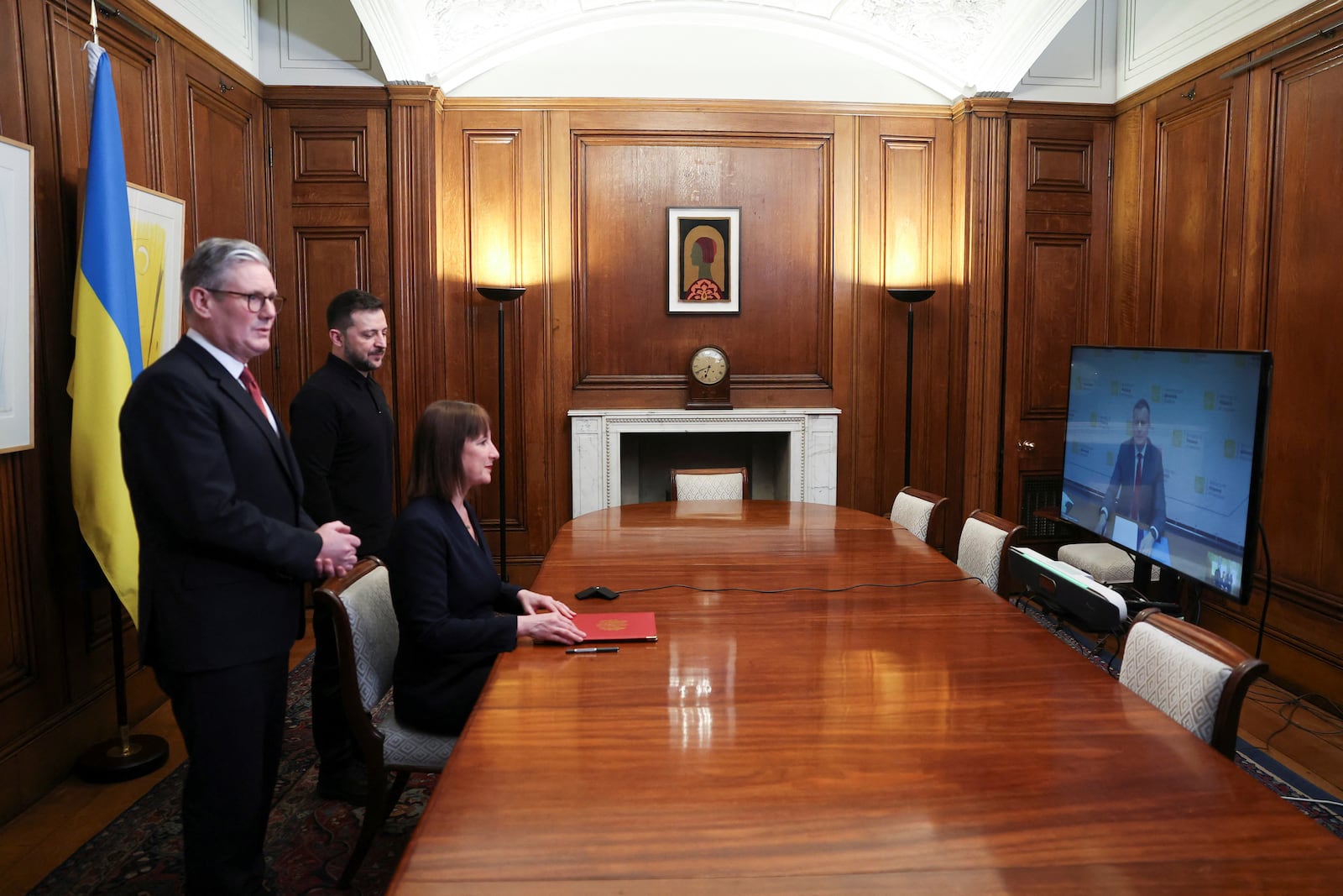 Britain's Chancellor of the Exchequer Rachel Reeves, left at the table, holds a document of defence lend for Ukraine on the day she holds a video conference meeting with Ukraine's Finance Minister Sergii Marchenko, as British Prime Minister Keir Starmer, left, and Ukrainian President Volodymyr Zelenskiyy, second left, stand in London, England, March 1, 2025. (Toby Melville/Pool Photo via AP)