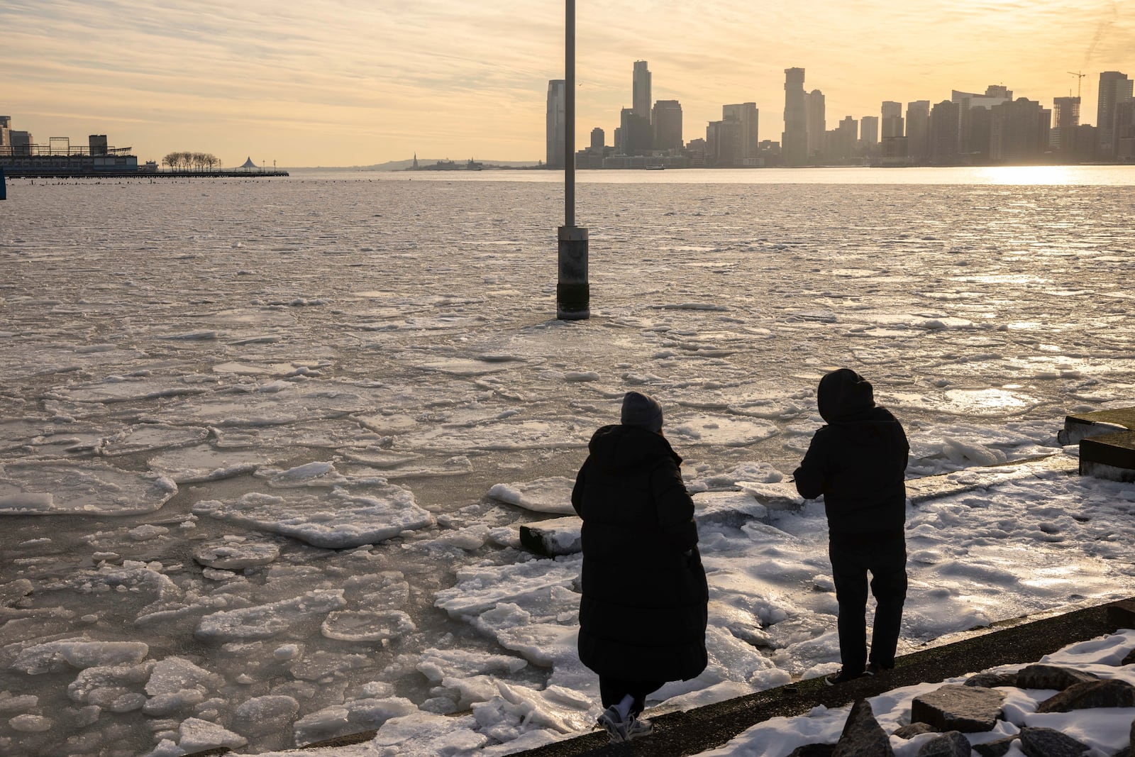 People walk along the pier as ice floats on the Hudson River, Thursday, Jan. 23, 2025, in New York. (AP Photo/Yuki Iwamura)