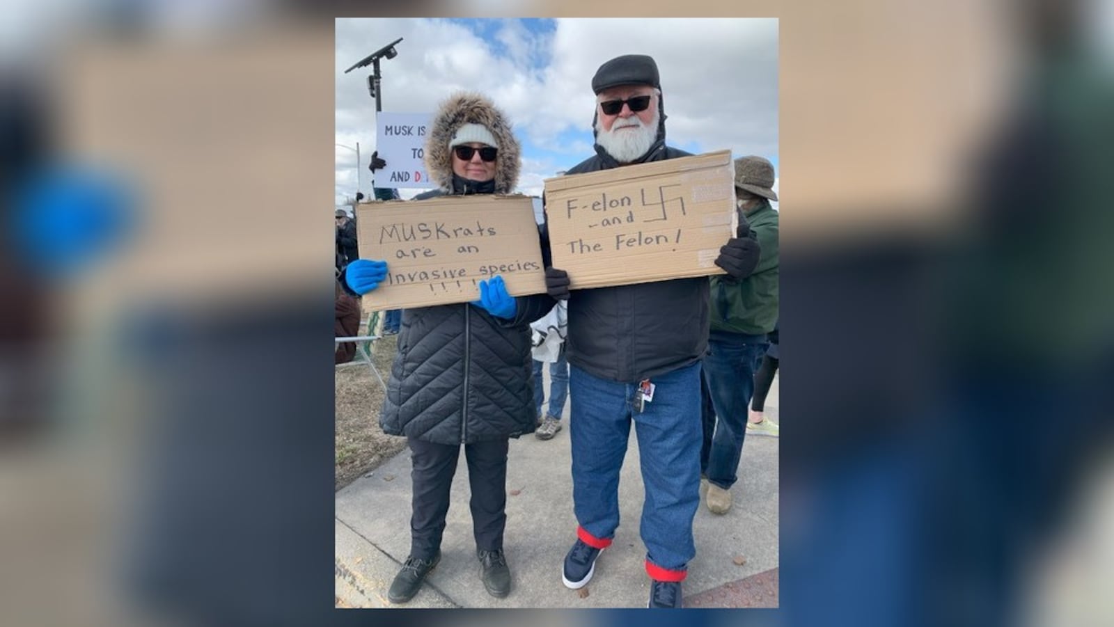 Hundreds of people lined West Dorothy Lane in Moraine on Saturday, March 1, 2025 to protest near a Tesla Service Center, including Carl and Suzanne Geisler (pictured). The protest was aimed at Elon Musk, the world's richest man, and his actions with the Trump administration and the Department of Government Efficiency. BROOKE SPURLOCK/STAFF