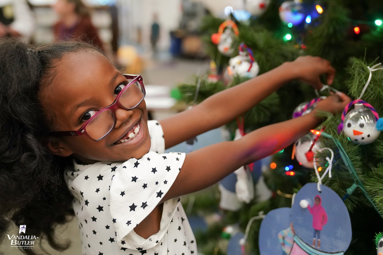 In Dec. 2022, students at Helke Elementary created handcrafted ornaments and decorated the tree in the school’s media center. Pictured is a student proudly choosing a place on the tree for her ornament. Courtesy of schools. 